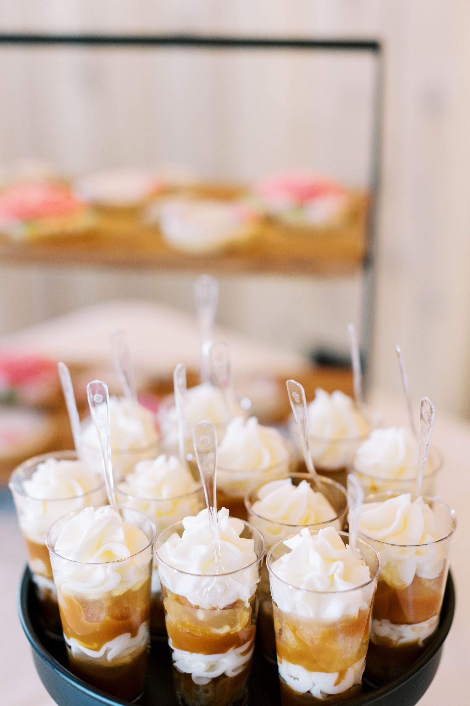 Mini dessert cups filled with whipped cream and caramel served on black trays.