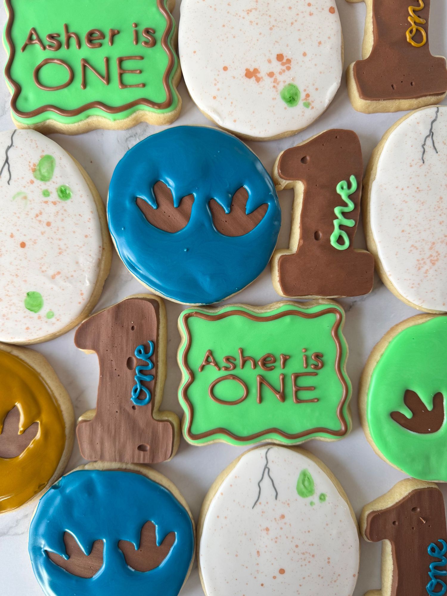 Custom decorated sugar cookies with green and blue icing for a first birthday celebration.
