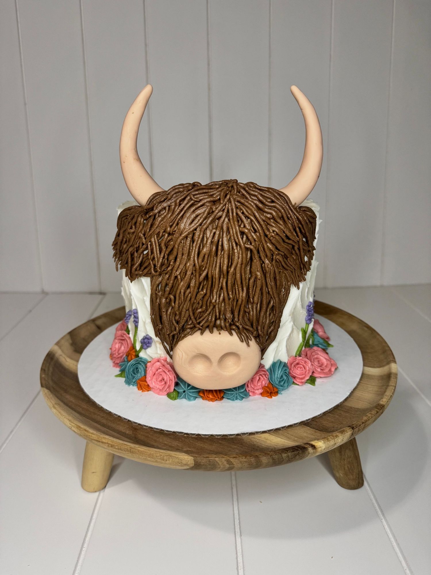 Cake decorated with brown textured horns and colorful floral accents.