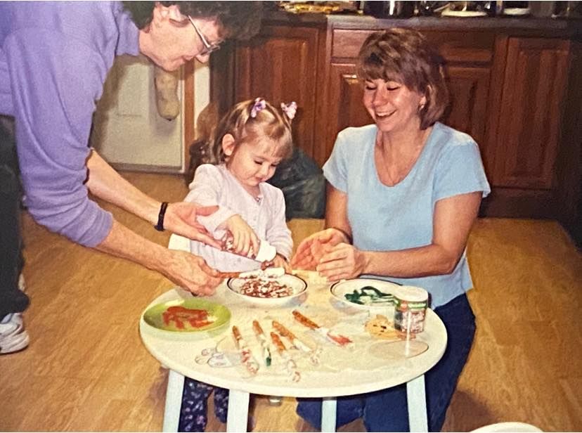 Hands working together to decorate a cake on a wooden table.