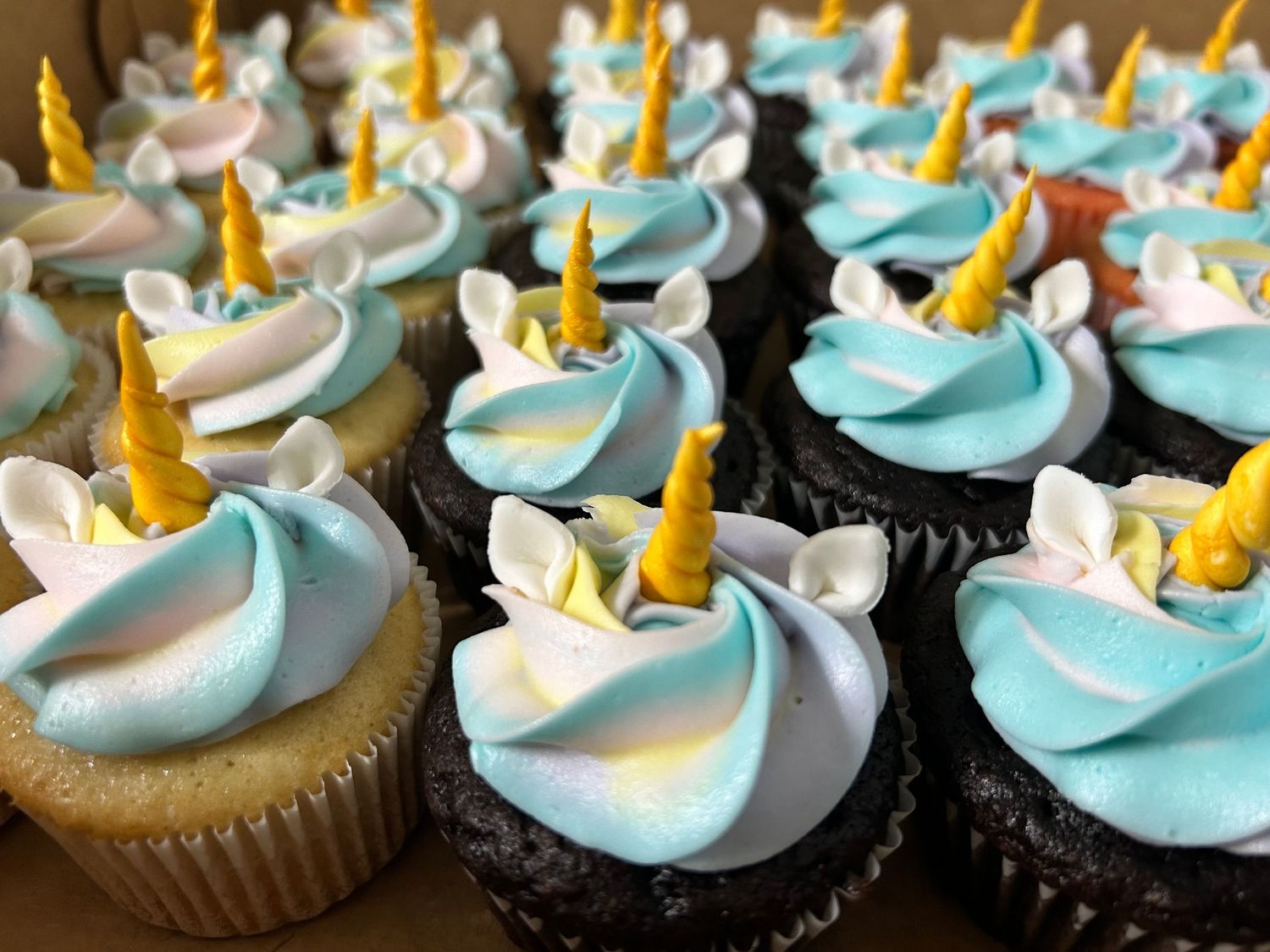 Cupcakes topped with blue and white swirled frosting and gold unicorn horn decorations.