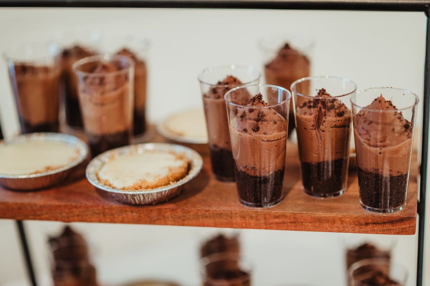 Chocolate desserts and drinks arranged on a rustic wooden table for a wedding reception.