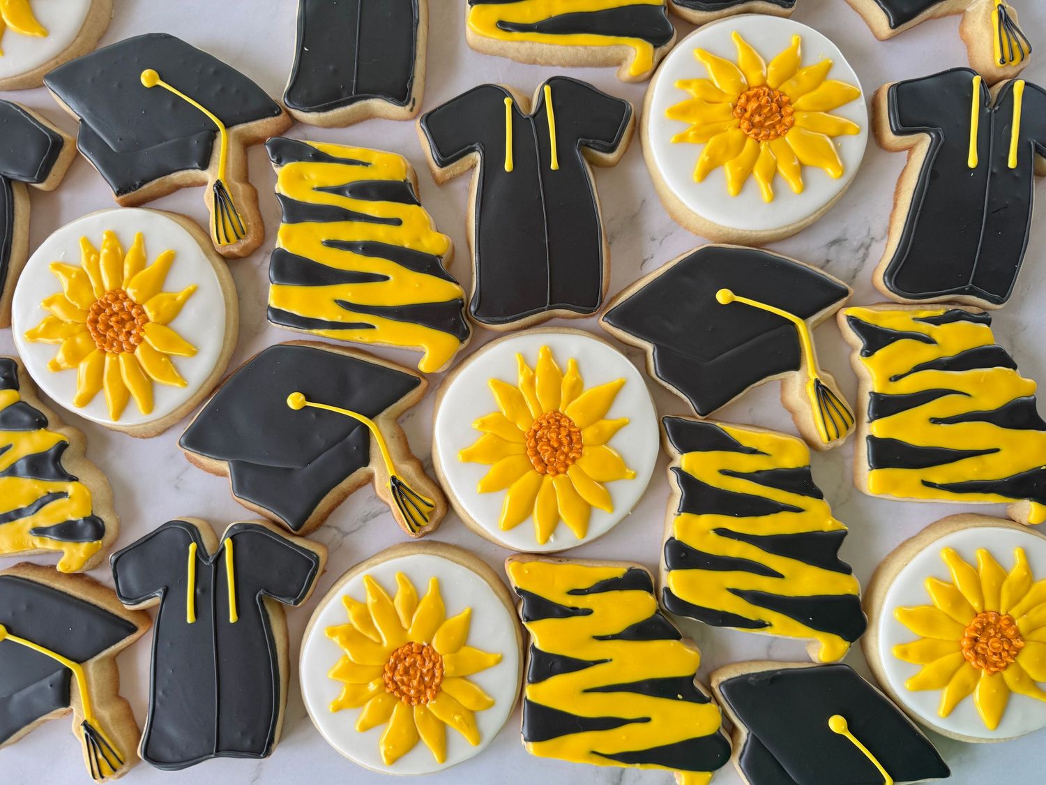 Black and yellow graduation cookies with sunflower designs and diploma decorations.