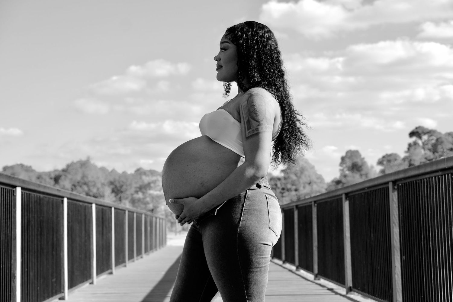 Black and white maternity photography session on outdoor wooden boardwalk.