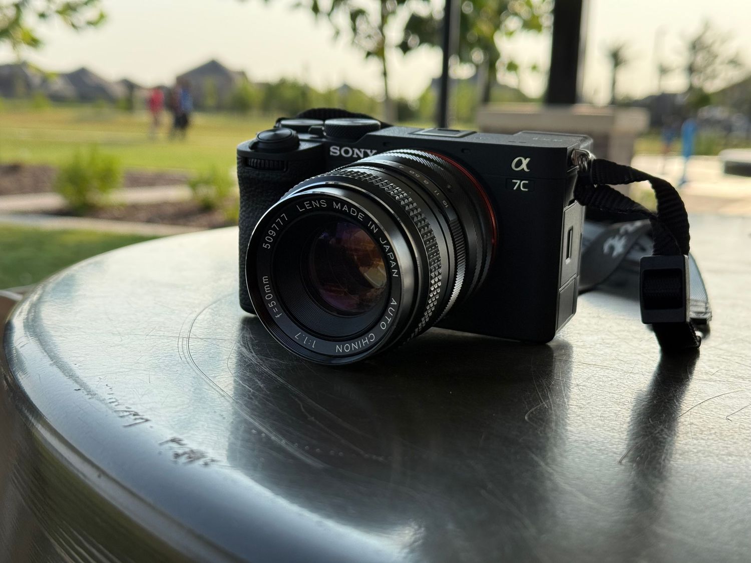 Black Sony Alpha mirrorless camera sitting on reflective surface in natural lighting.