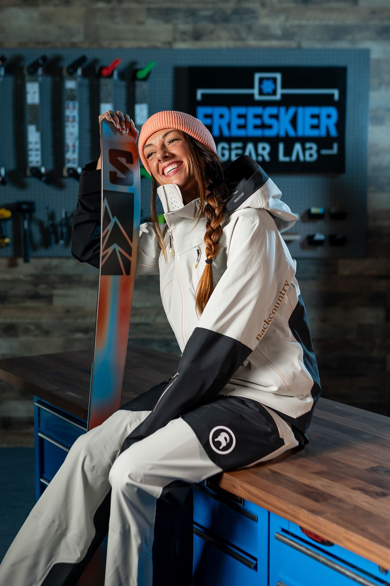 Person in white winter sportswear relaxing on bench at indoor ski equipment shop.