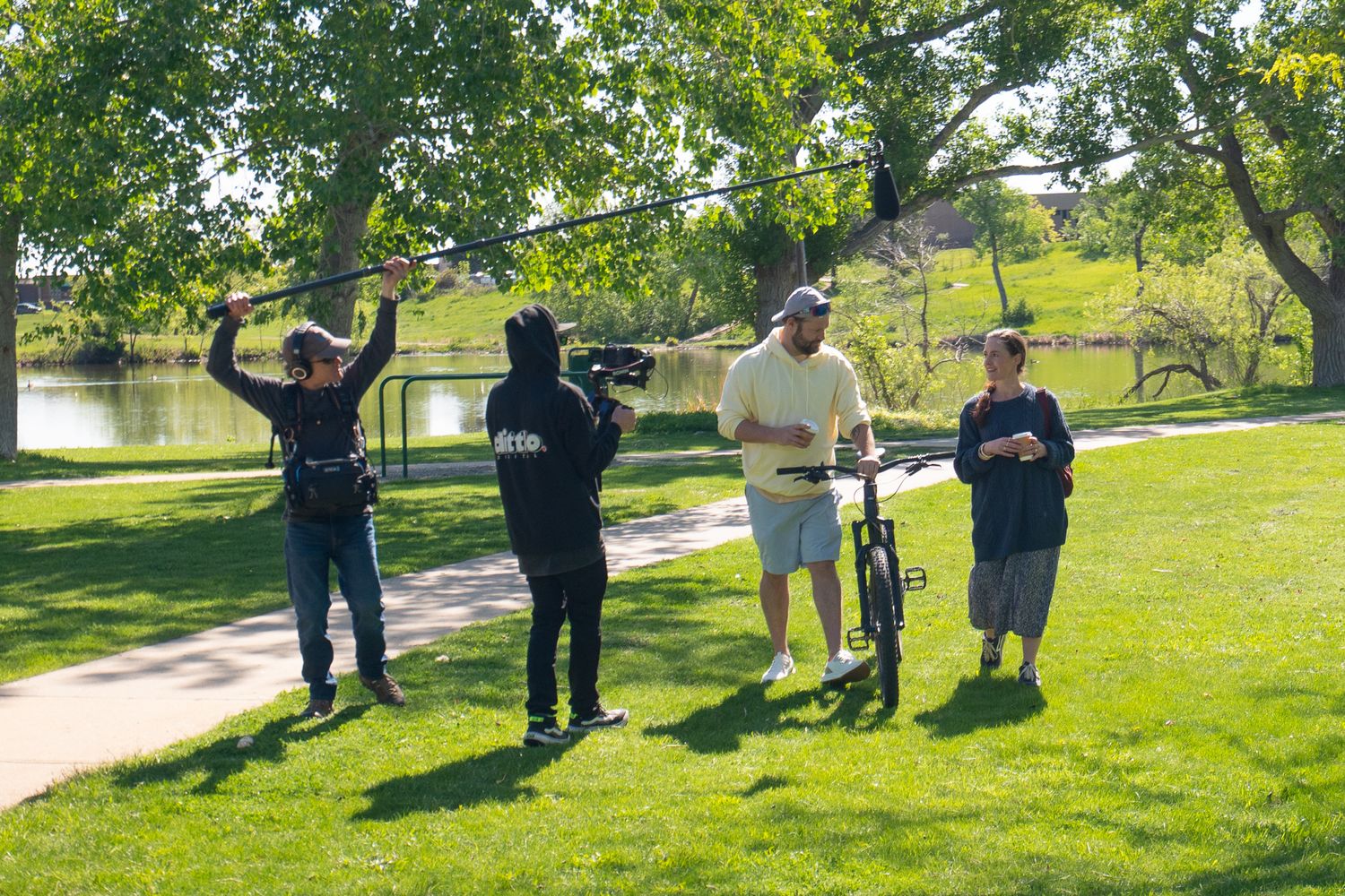 People playing disc golf in a sunny park with trees and green grass.