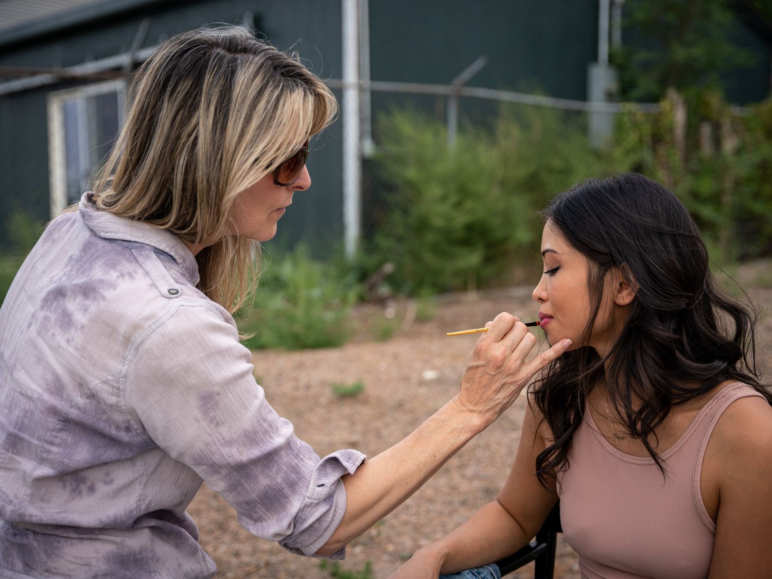 Behind the scenes makeup application during outdoor film production shoot.