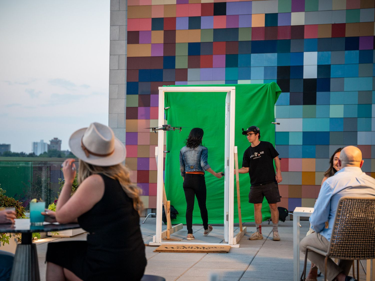 Production team filming against a colorful geometric wall pattern on an urban rooftop.