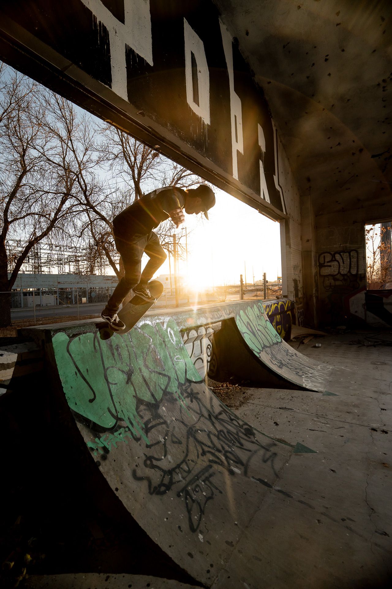 Silhouette of skateboarder on ramp against sunset in urban skate park.