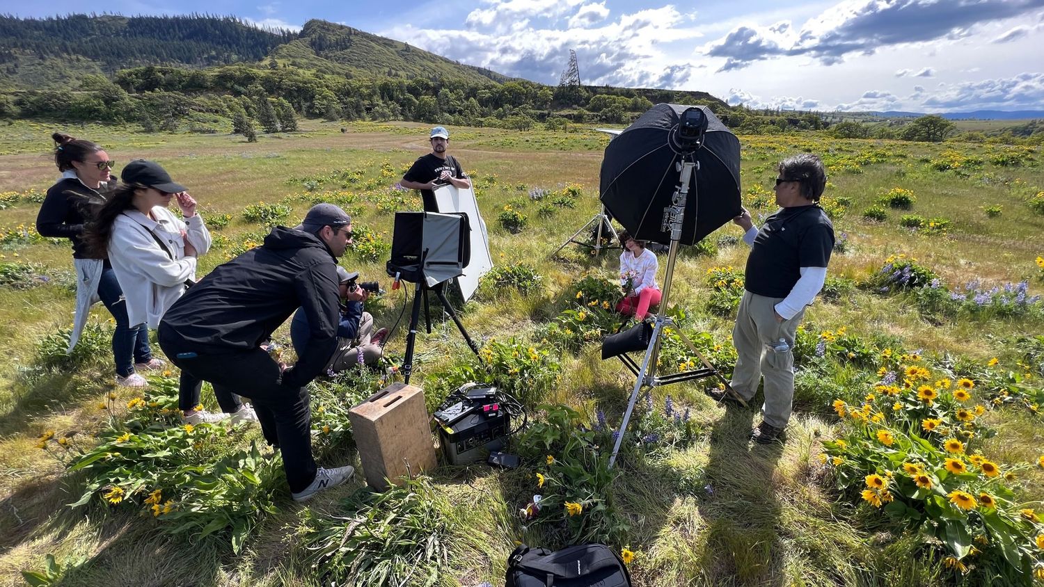 Photographers and nature enthusiasts gather in a wildflower meadow to capture scenic mountain landscapes.