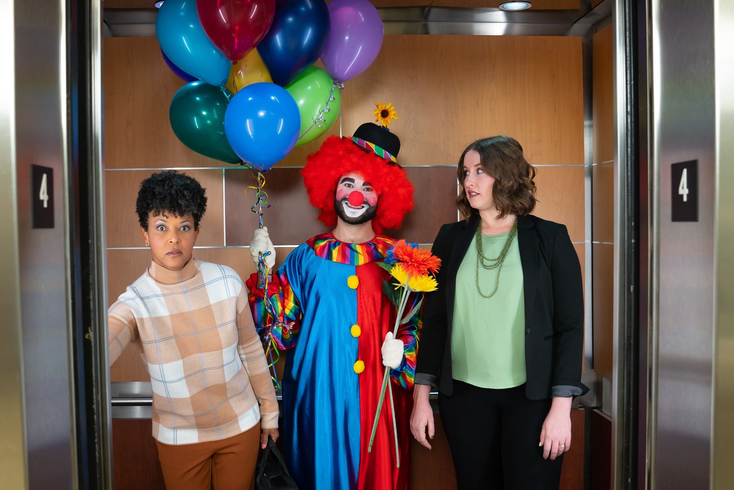 Cheerful clown with colorful balloons posing in elevator with two others.