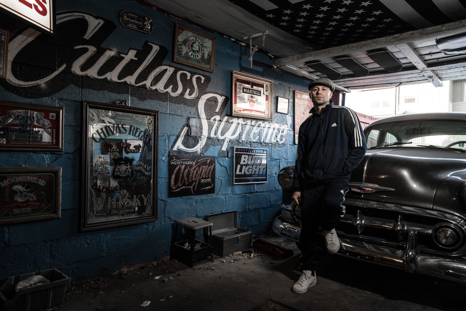 Interior of custom auto shop with vintage cars and neon signage creating moody atmosphere.