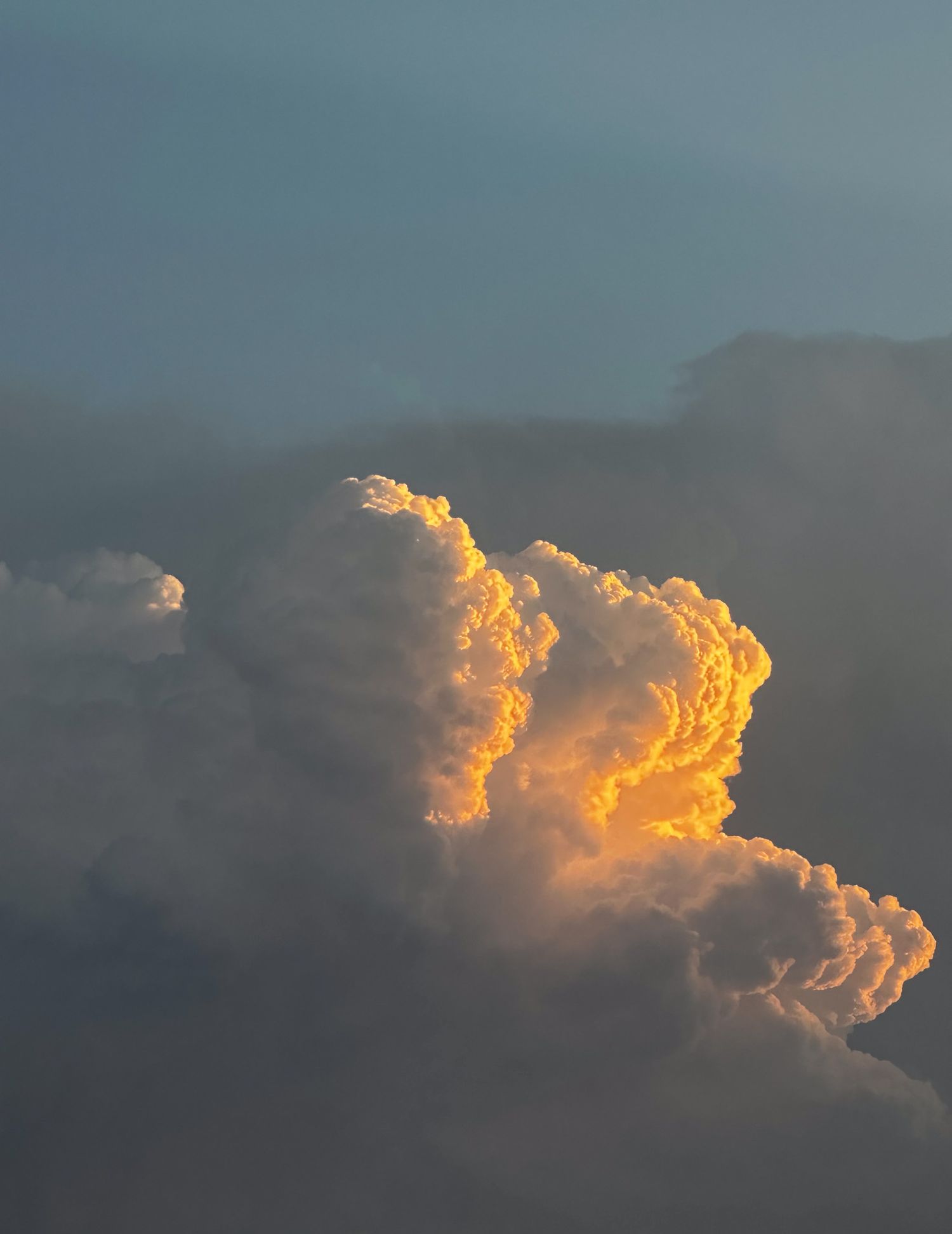 Orange-tinted clouds glow dramatically during sunset against a blue-gray sky.