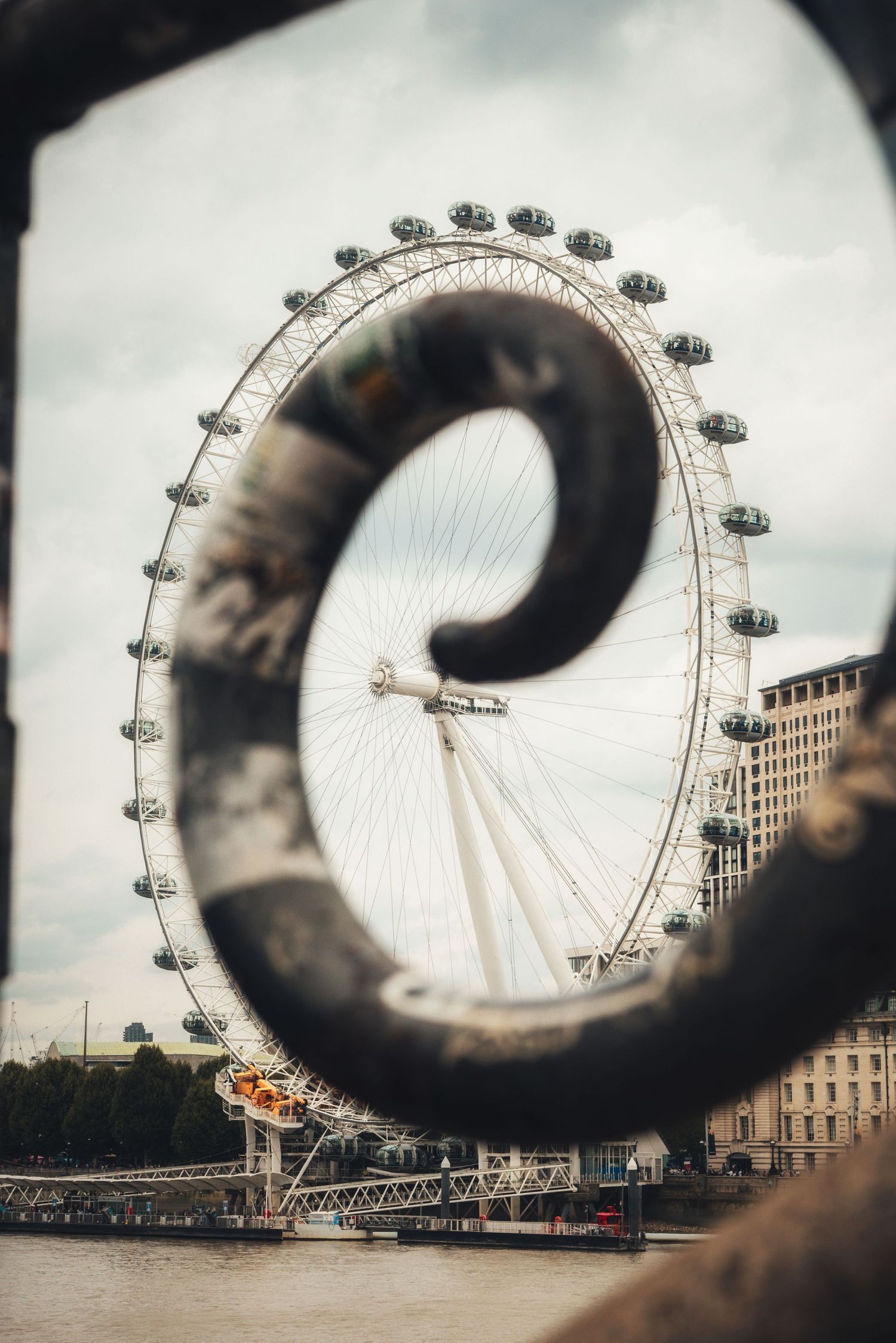 The London Eye in London, England, creatively framed through a decorative spiral wrought-iron railing.