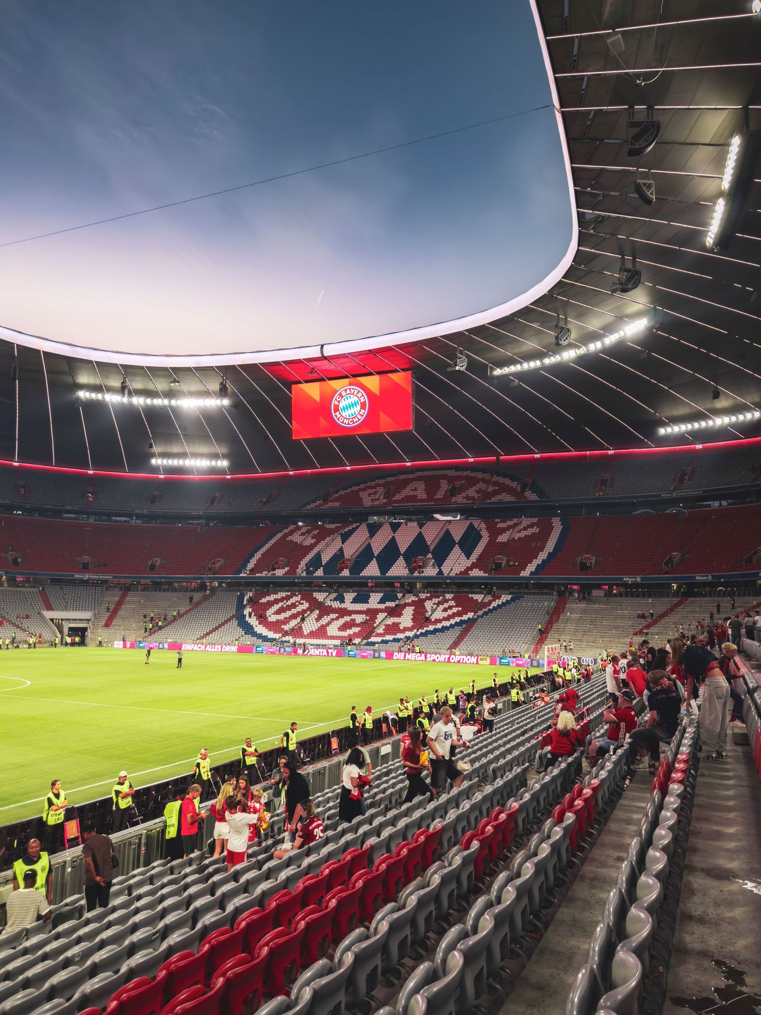 The stands of the Allianz Arena in Munich, Germany after a Bundesliga match, featuring the large FC Bayern München seat logo.
