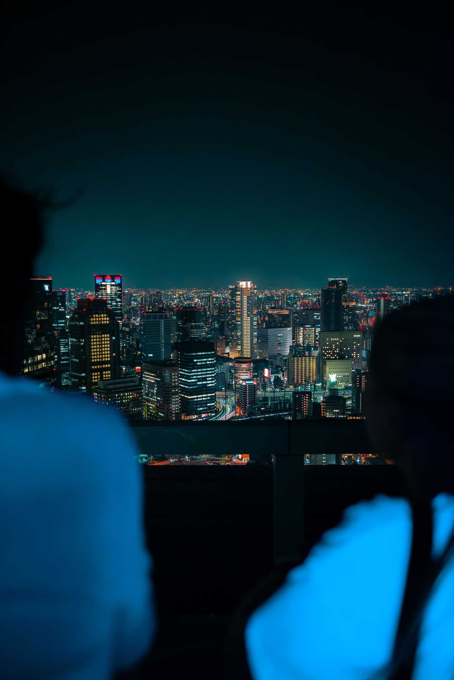 View of the Osaka, Japan city skyline illuminated at night, seen from the observation deck of the Umeda Sky Building.