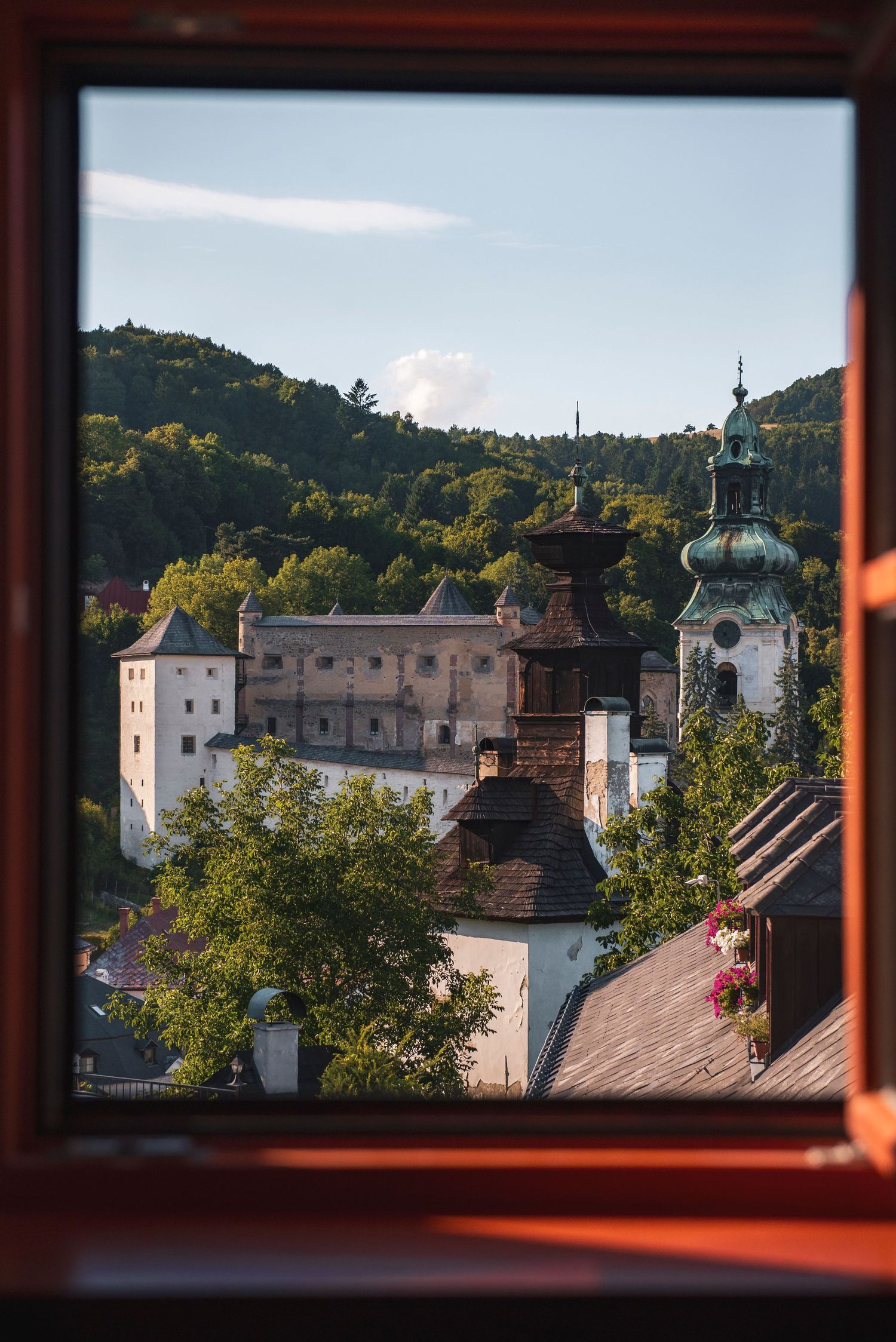 View of the Old Castle (Starý zámok) in Banská Štiavnica, Slovakia, framed through a wooden window at Hotel Resla Residence.