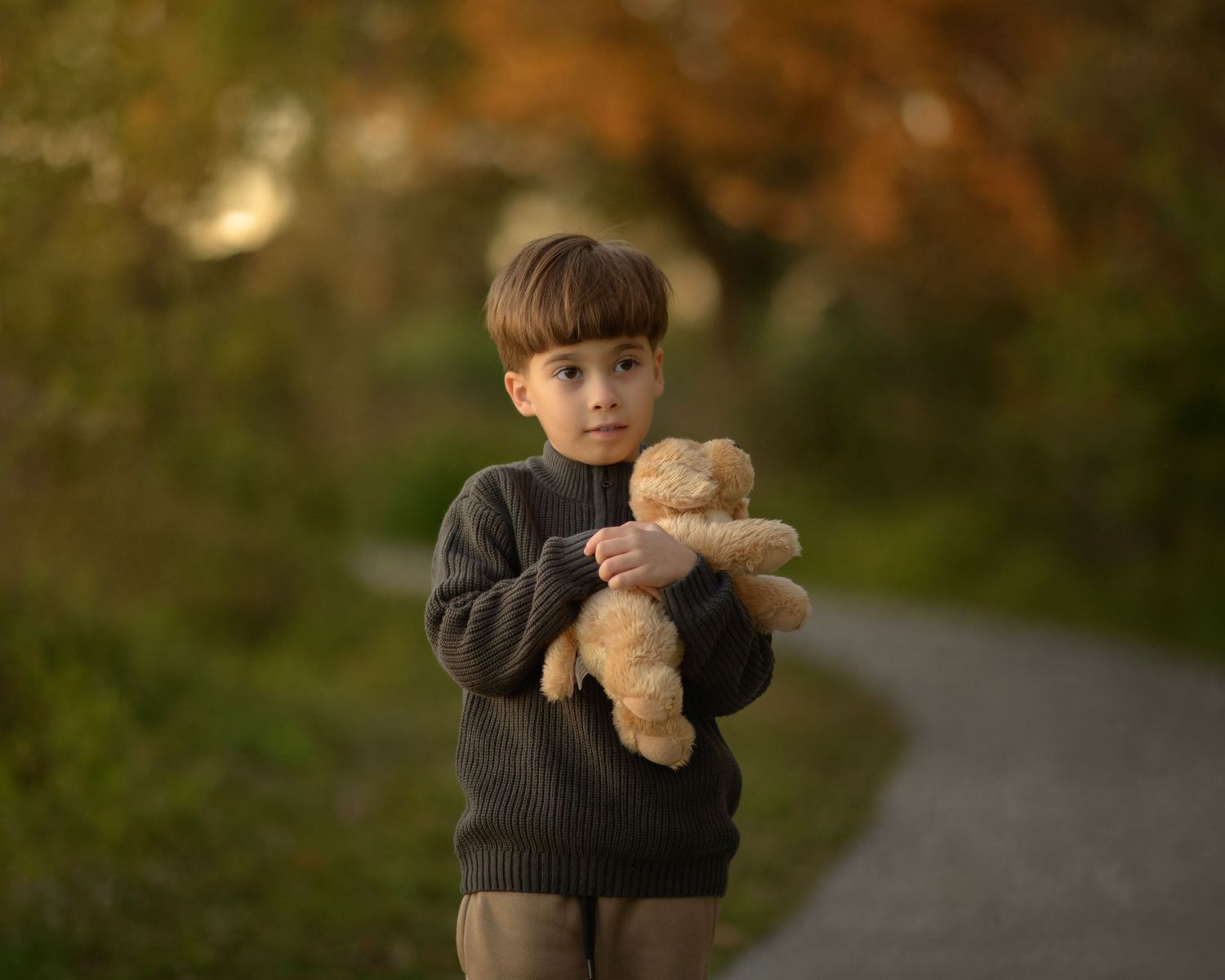 Autumn portrait holding teddy bear with fall colors in background.