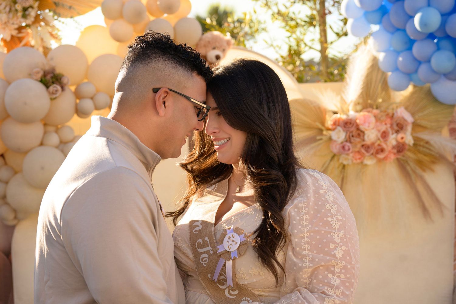 Couple embracing in front of elegant balloon arch during sunset celebration.