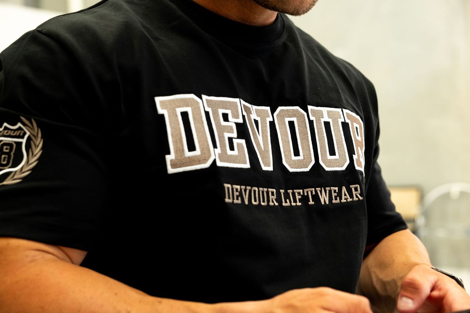 Person wearing black Devout Liftwear t-shirt showing text detail on fitness apparel.