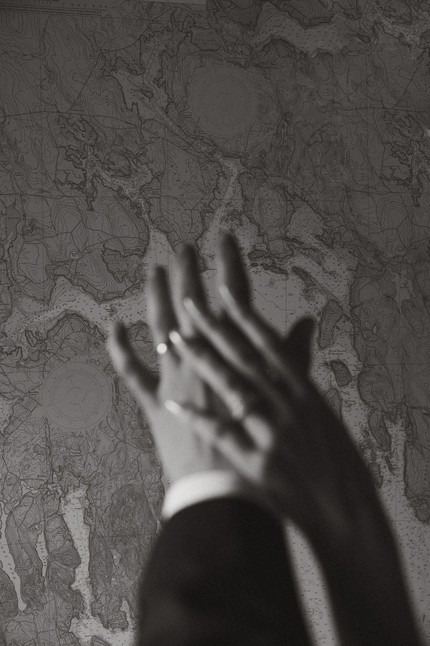 Black and white wedding detail photo with hands reaching toward a map of Maine before an Acadia National Park elopement.