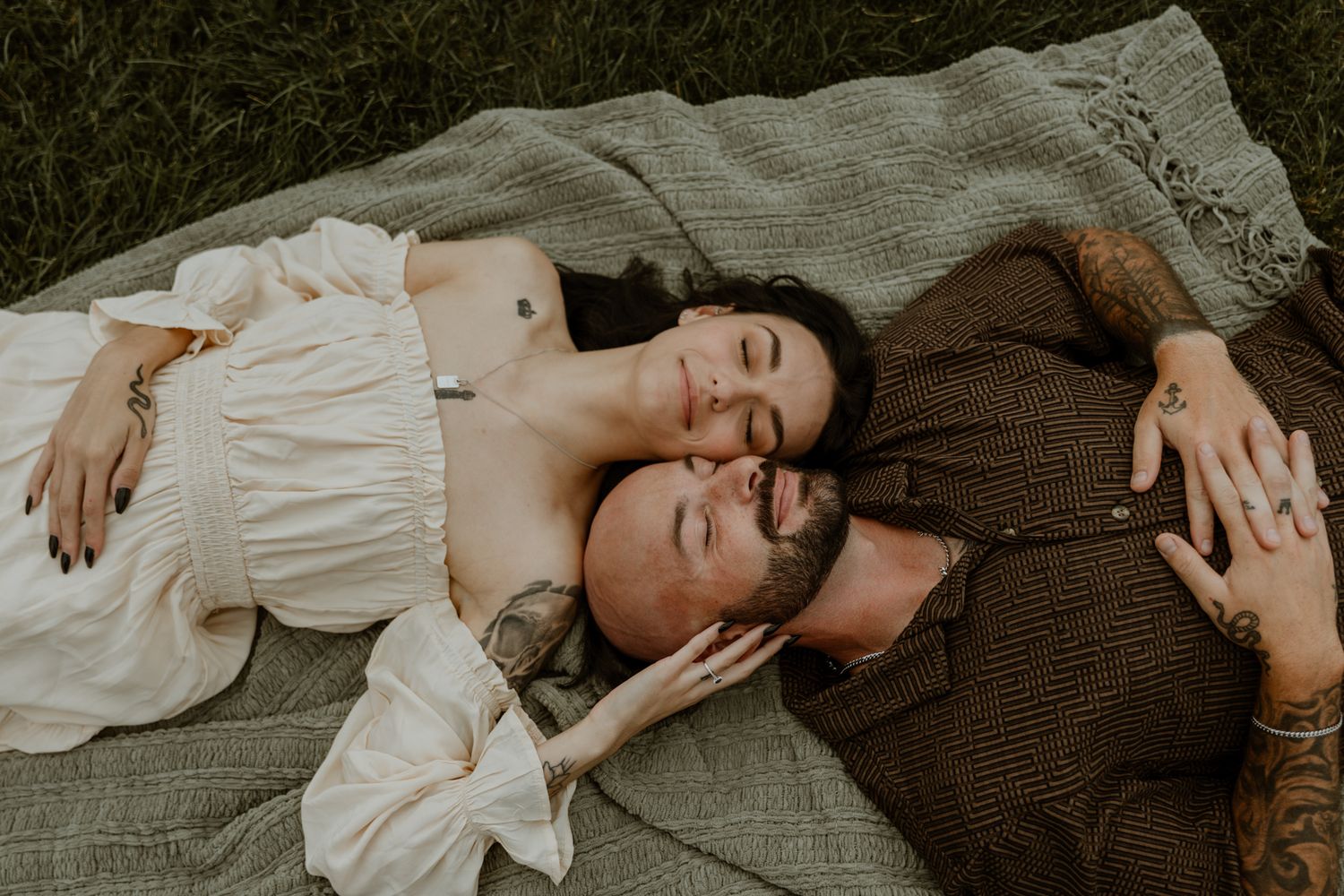 Couple lying together on grass during an outdoor photo session.