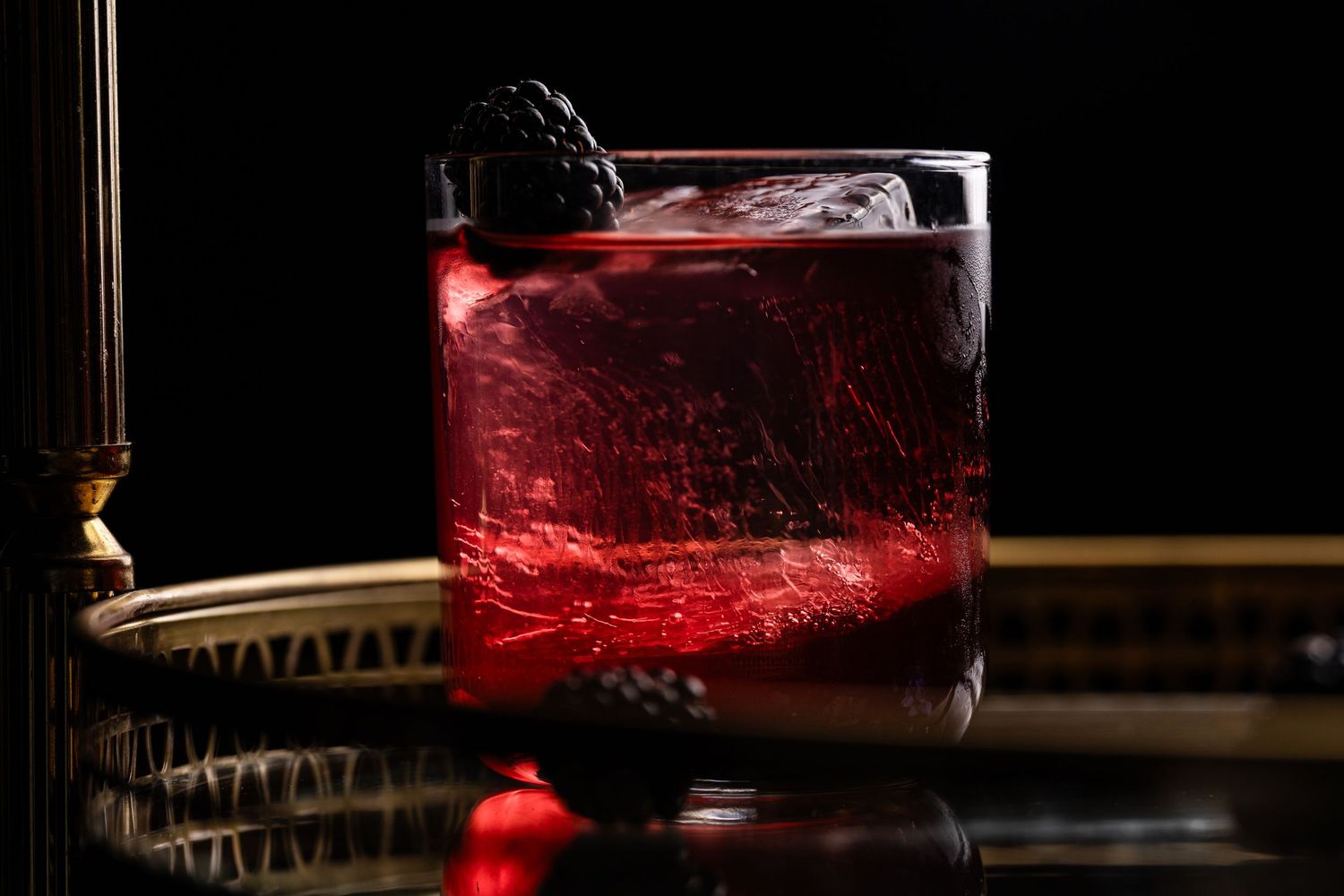 Dark moody still life with glowing red accents and glass objects in low key lighting.
