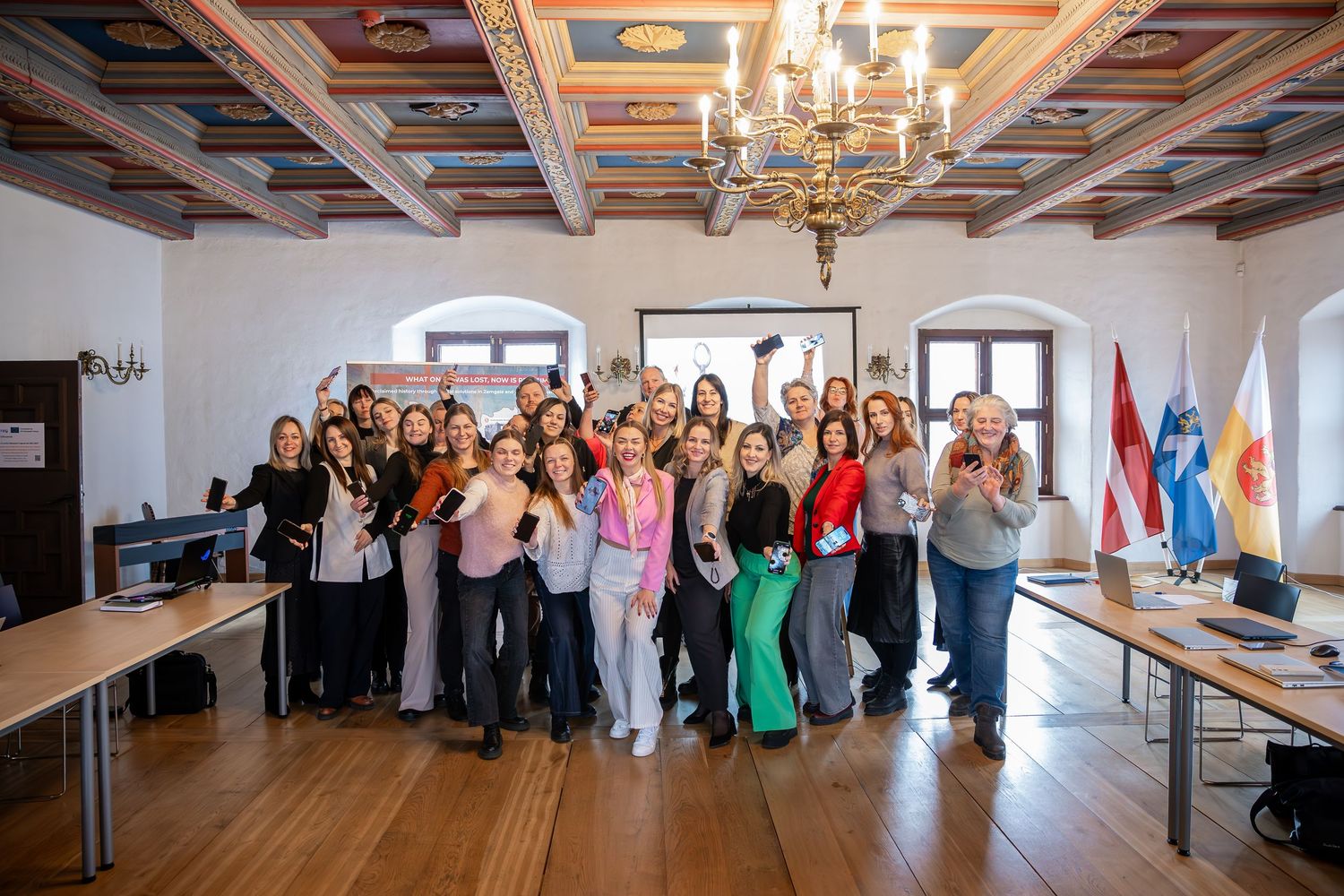 A panoramic view of a group gathering in a bright, modern office space with white walls and wooden floors.