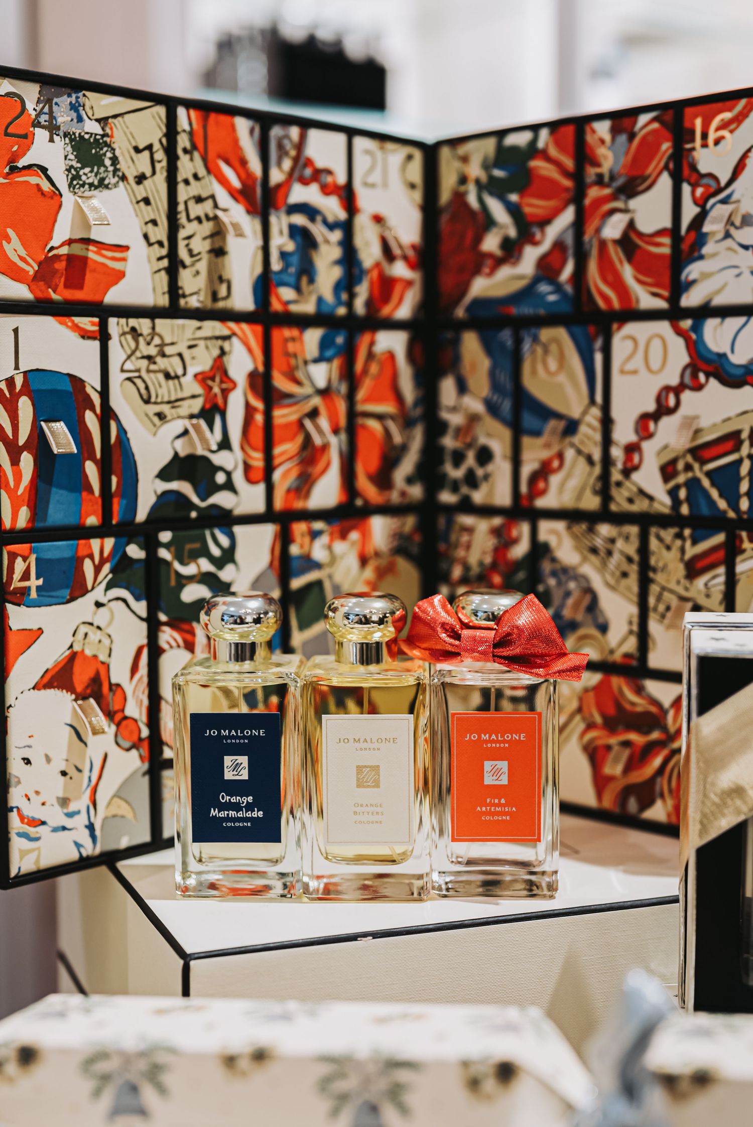 Luxury perfume bottles displayed against a colorful artistic backdrop with red accents.