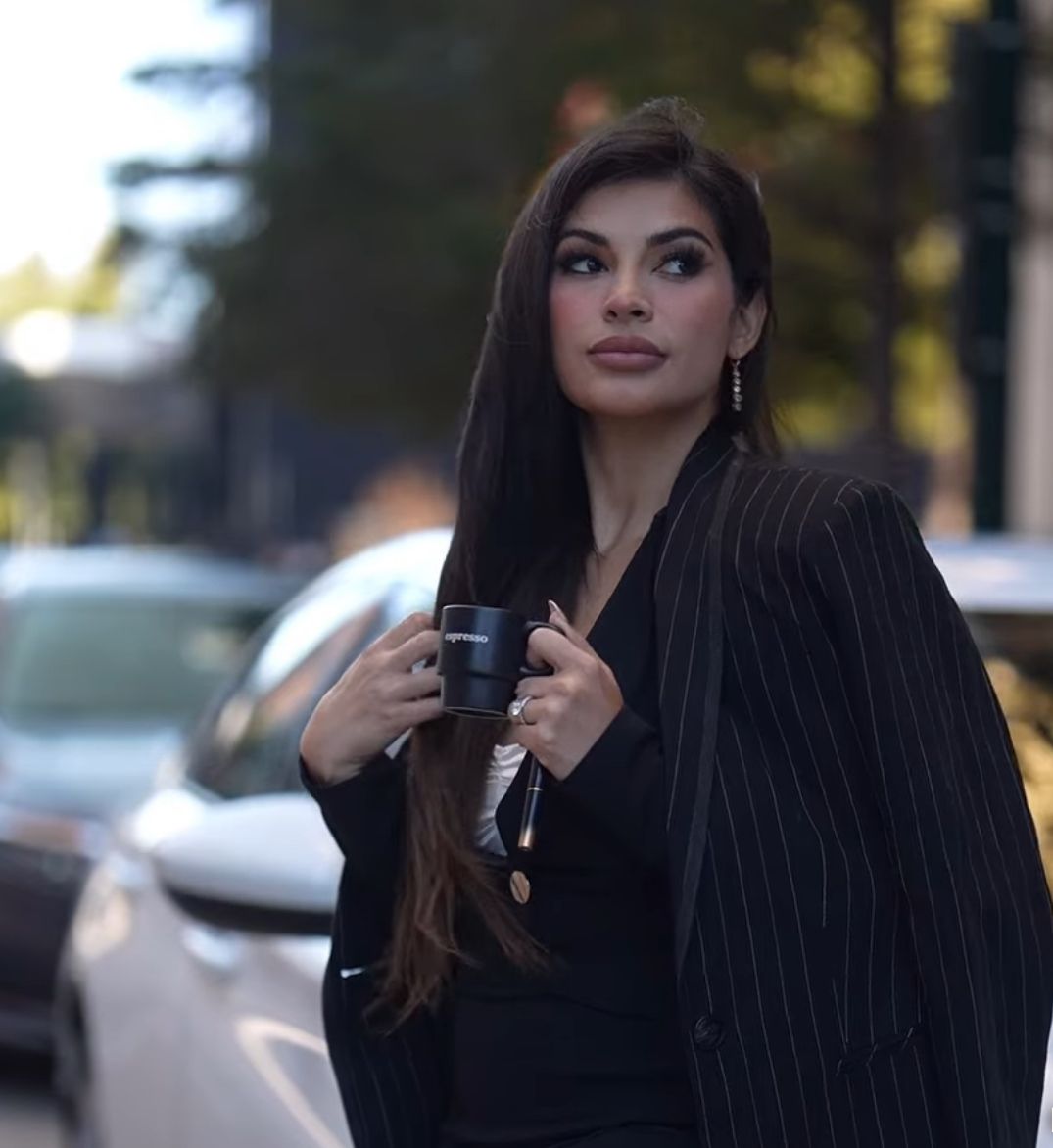 Elegant portrait in pinstriped blazer with long dark hair during outdoor photoshoot.
