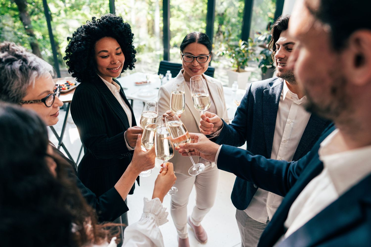 Colleagues toasting with wine glasses at an outdoor business celebration.