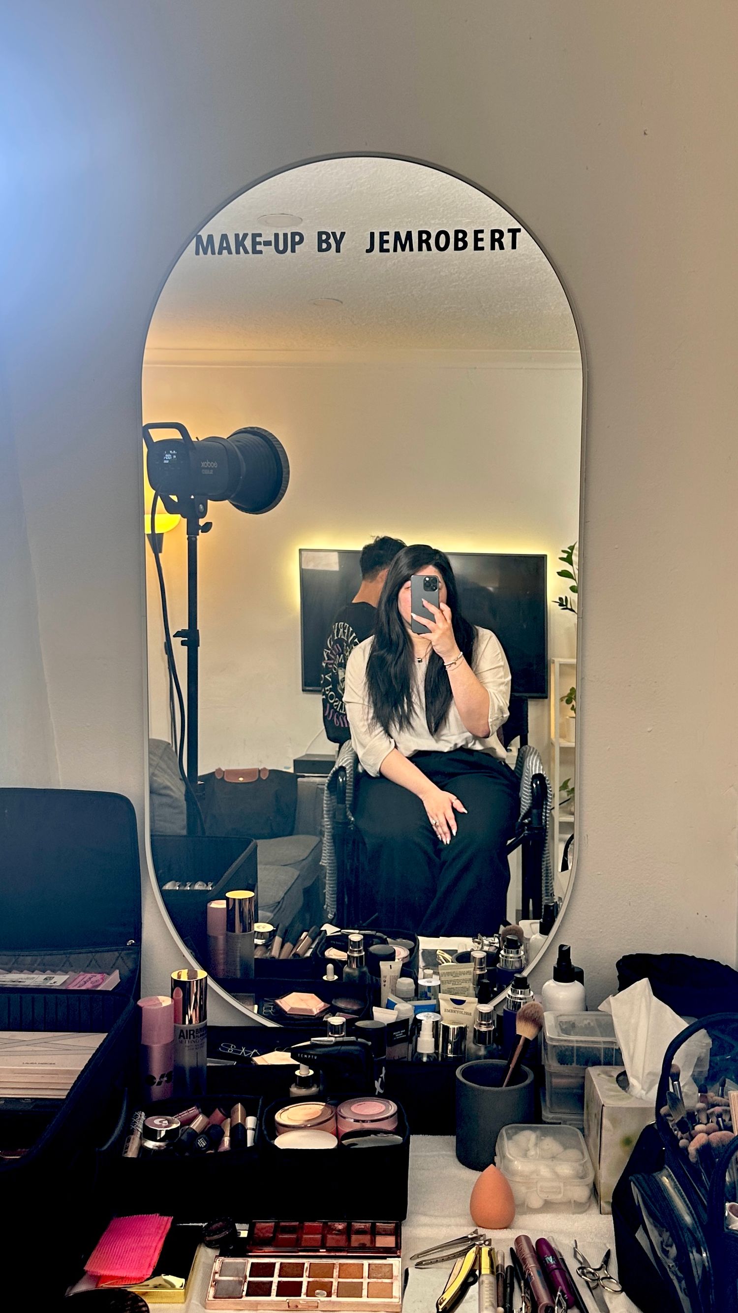 Professional makeup station with mirror, lighting equipment and cosmetics displayed.
