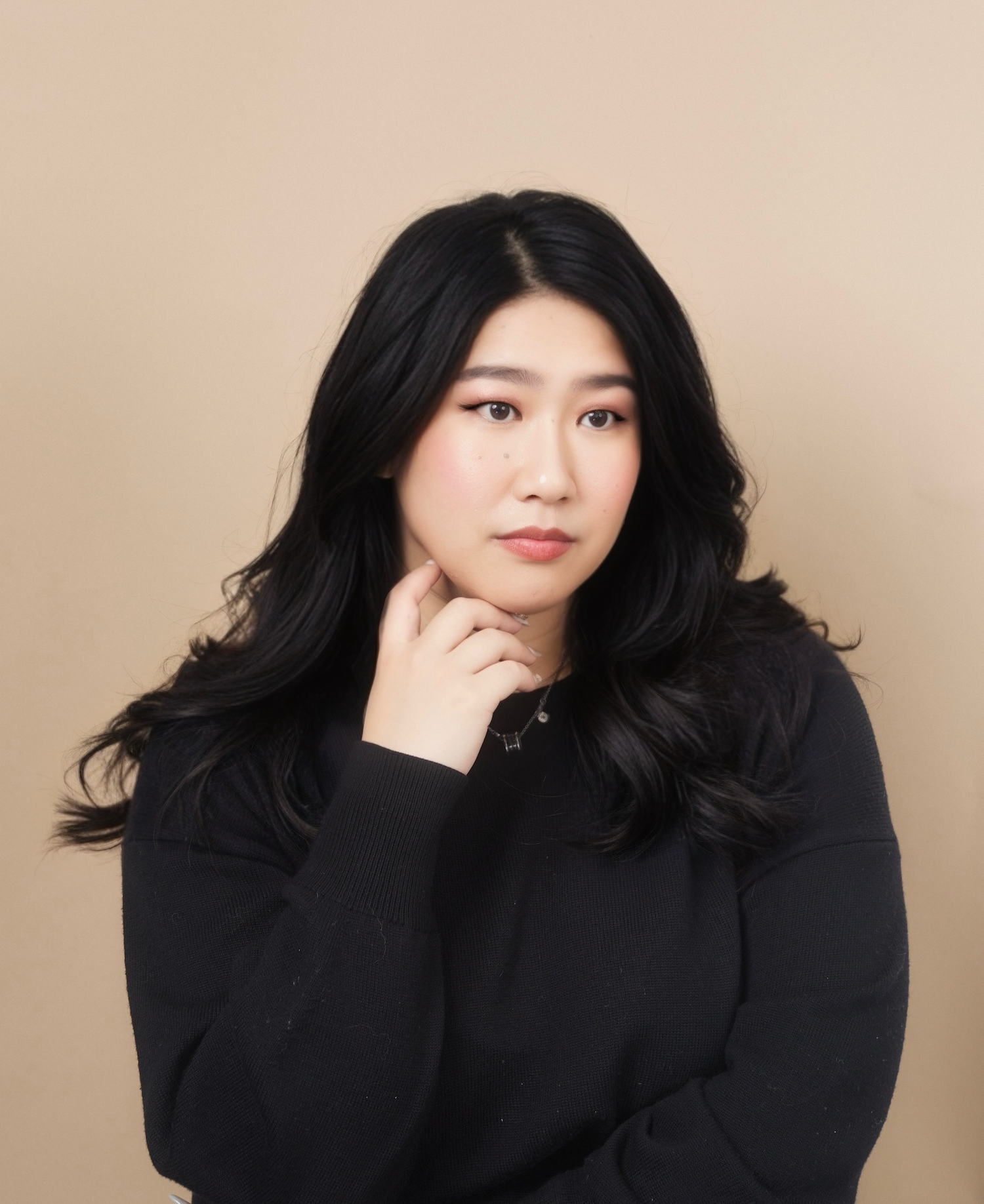 A series of five artistic portraits showing a person with long black hair wearing a black sweater against a neutral background.