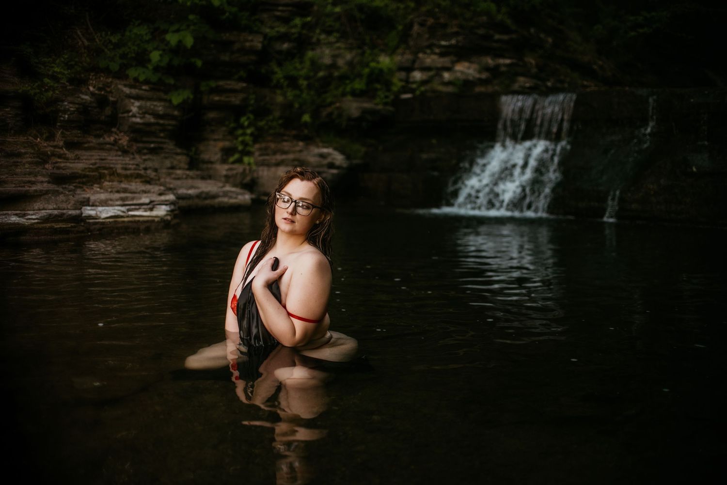 Romantic waterfall photoshoot with couple in natural setting at dusk.
