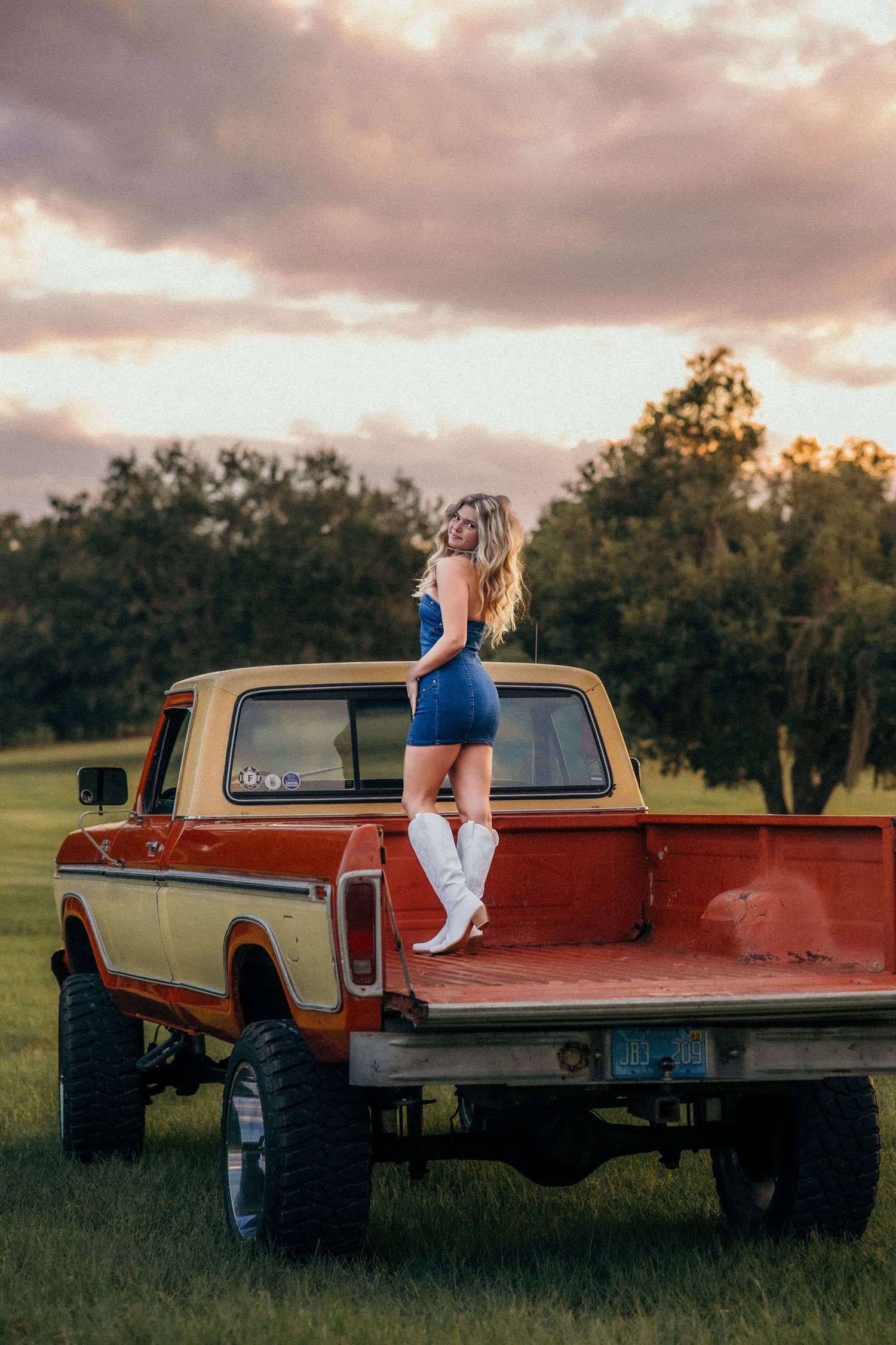 Retro trucks displayed in rural setting with dramatic sunset sky.