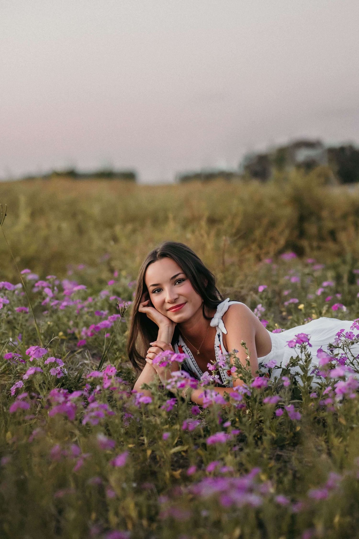 Someone lying in field of purple wildflowers during sunset photoshoot.