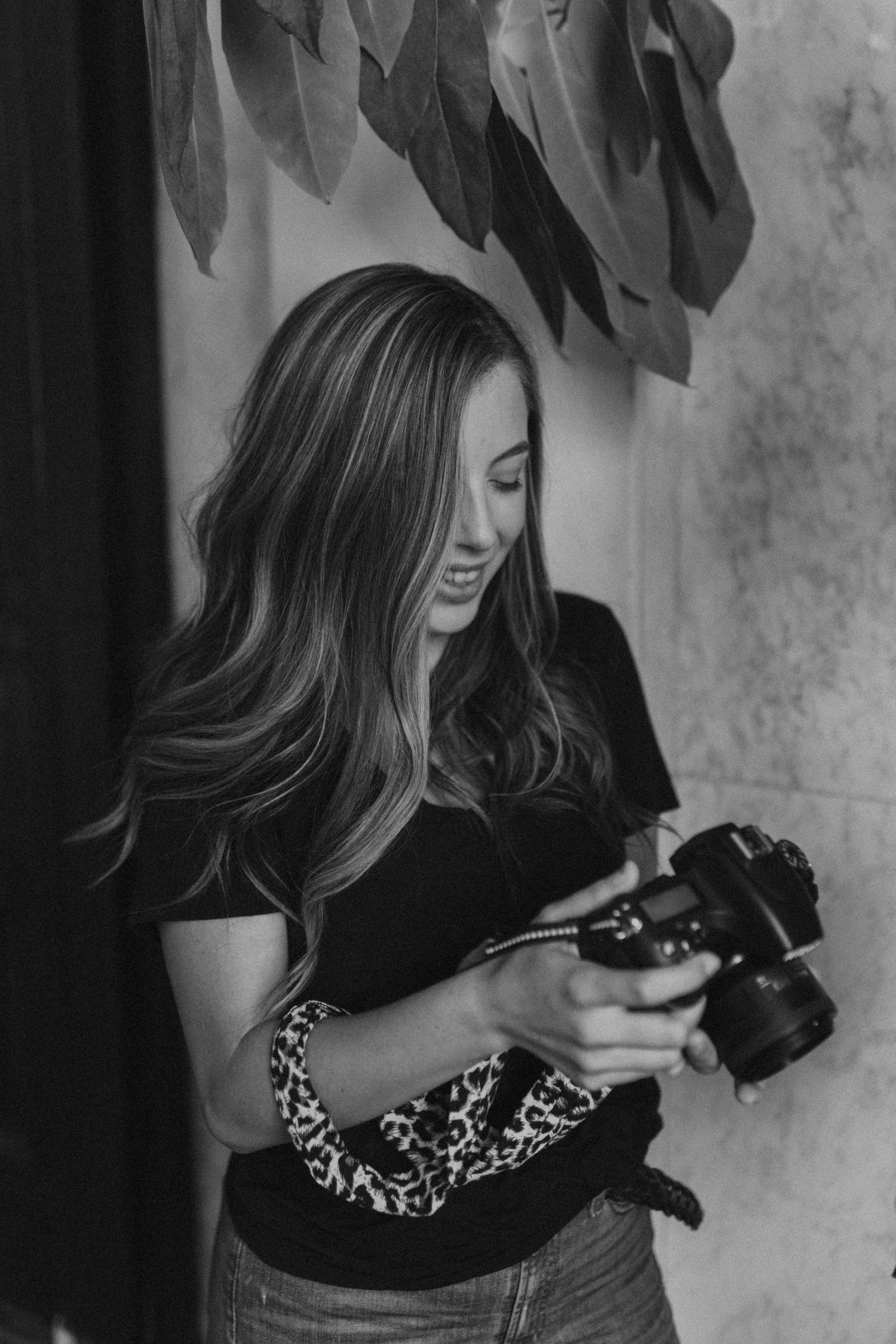 A black and white portrait of a photographer reviewing images on her camera.