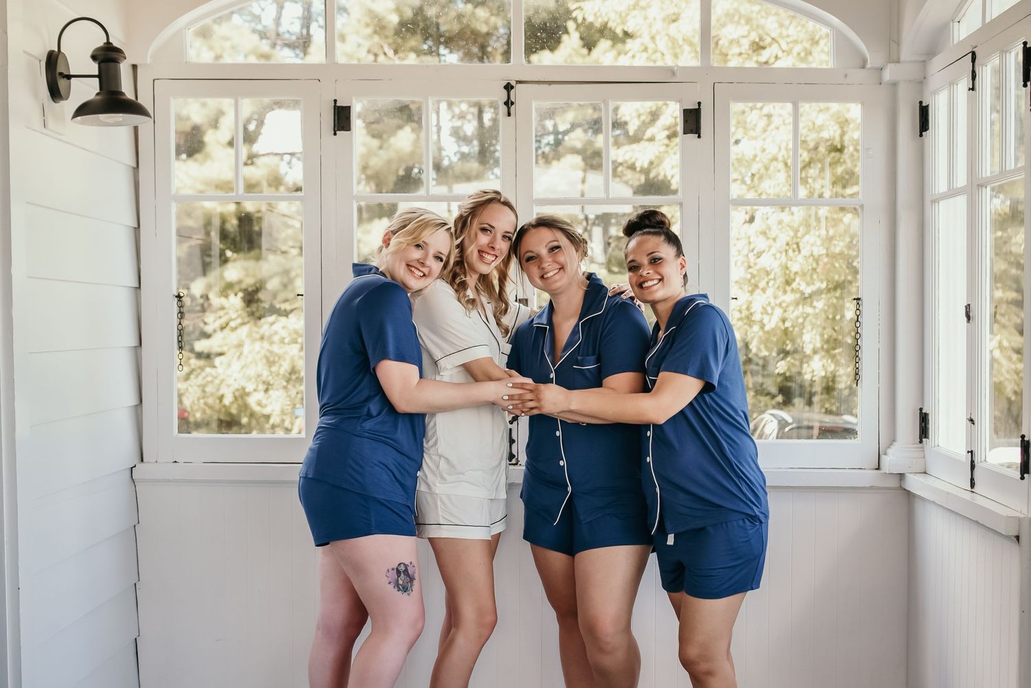 Group poses playfully in bright sunlit room with white walls and large windows.