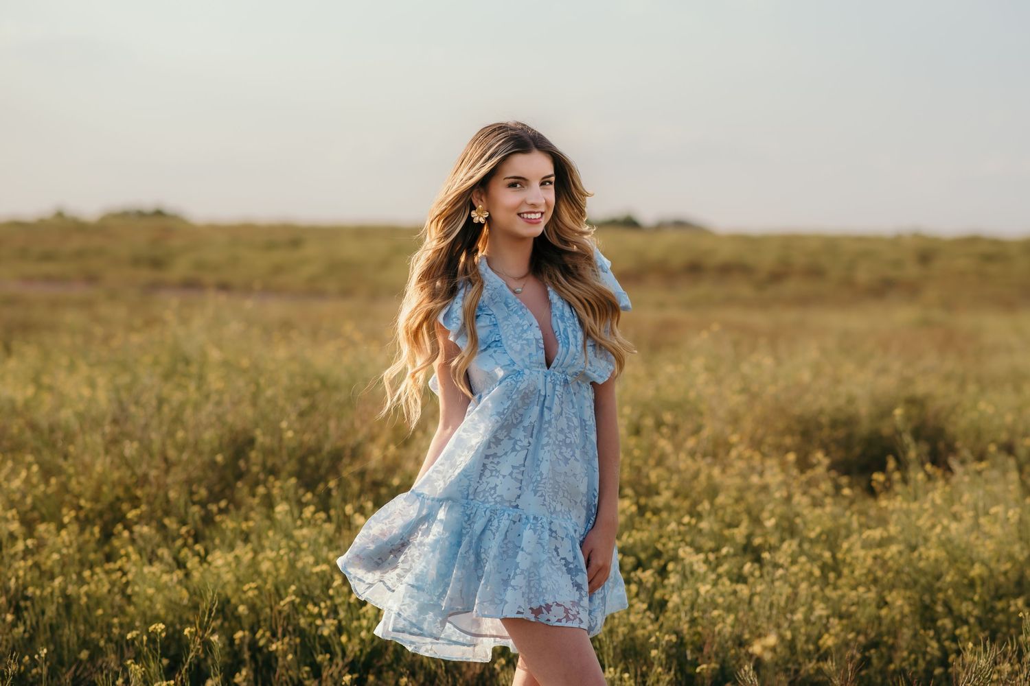 Summer fashion shoot in blooming field with light blue floral top.