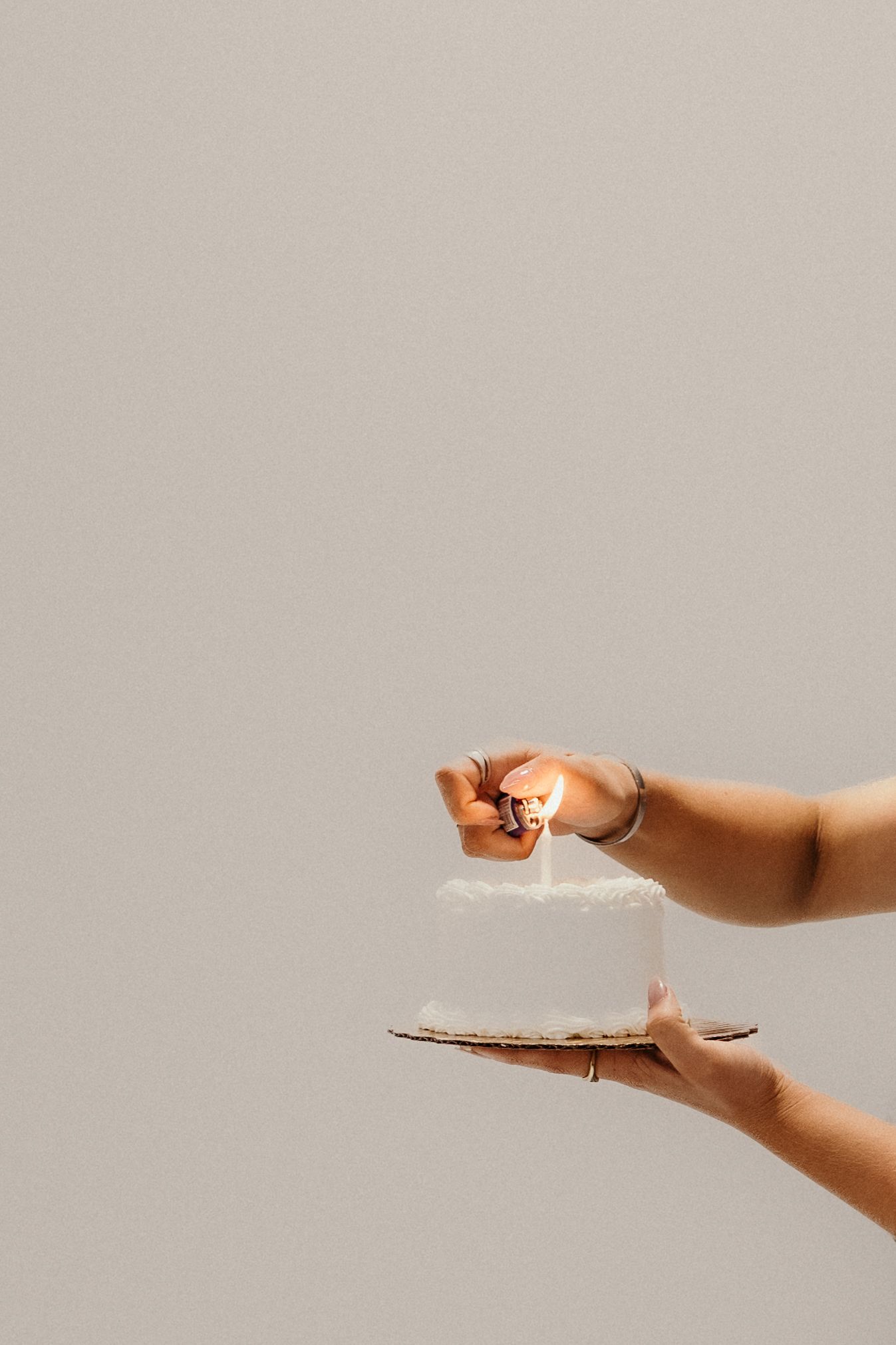 Two hands reach out against a neutral background to grasp a small white object between them.