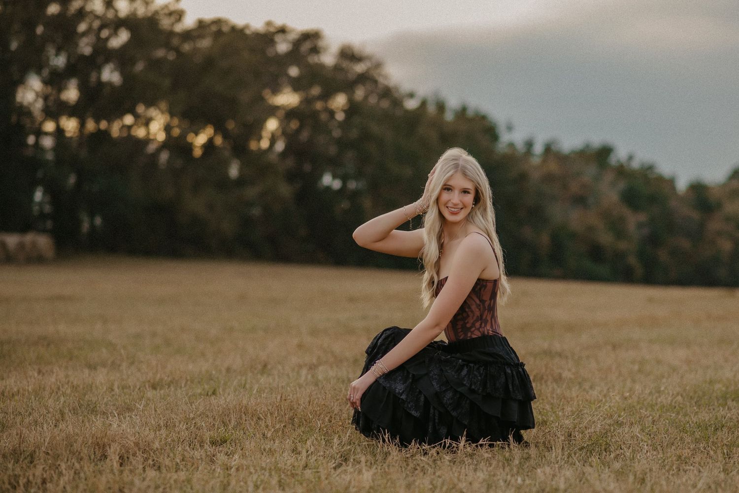 A series of artistic outdoor portraits showing a person in a black dress posing gracefully in a golden field at sunset.
