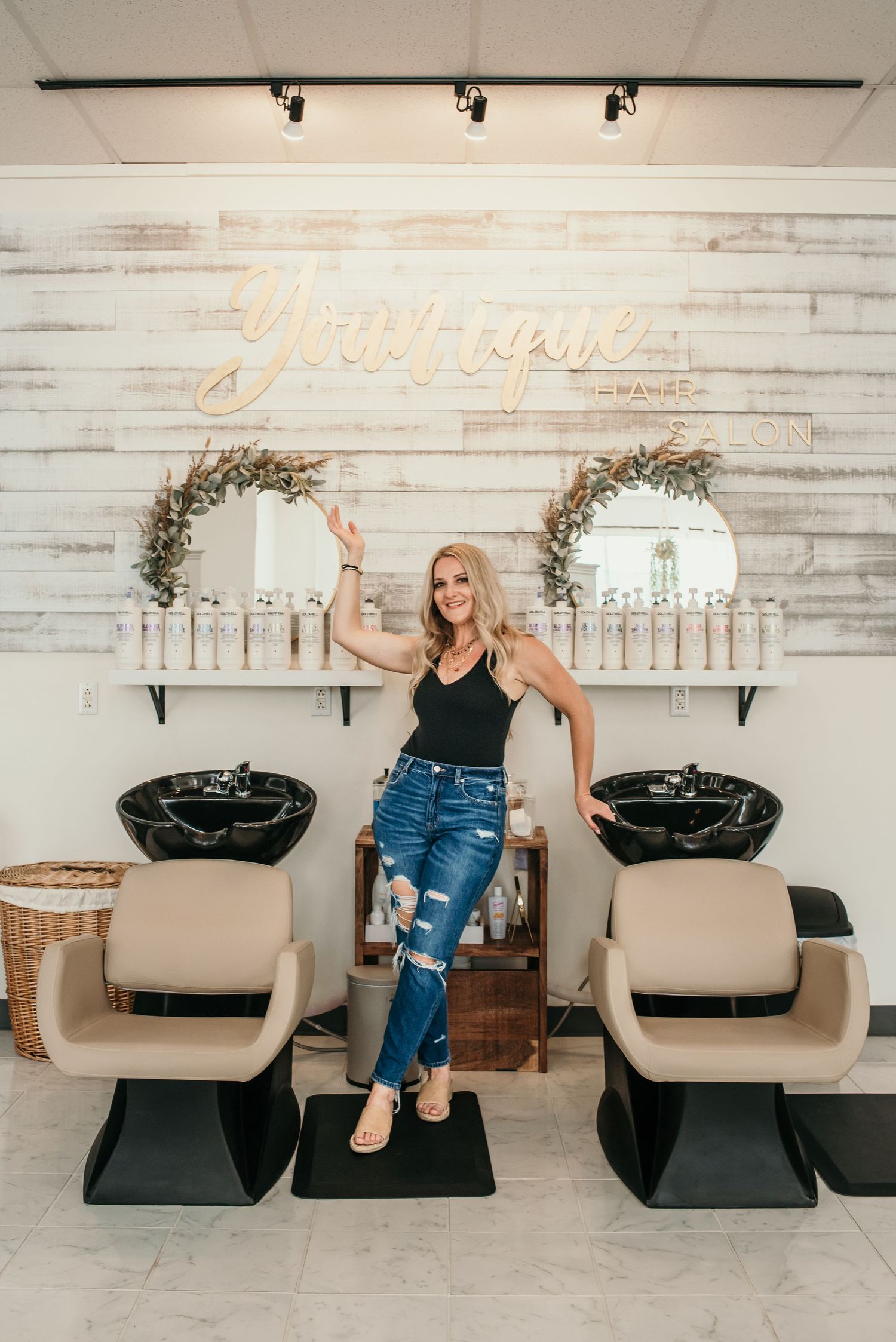 Interior of a modern hair salon with white chairs and rustic wood paneled wall.
