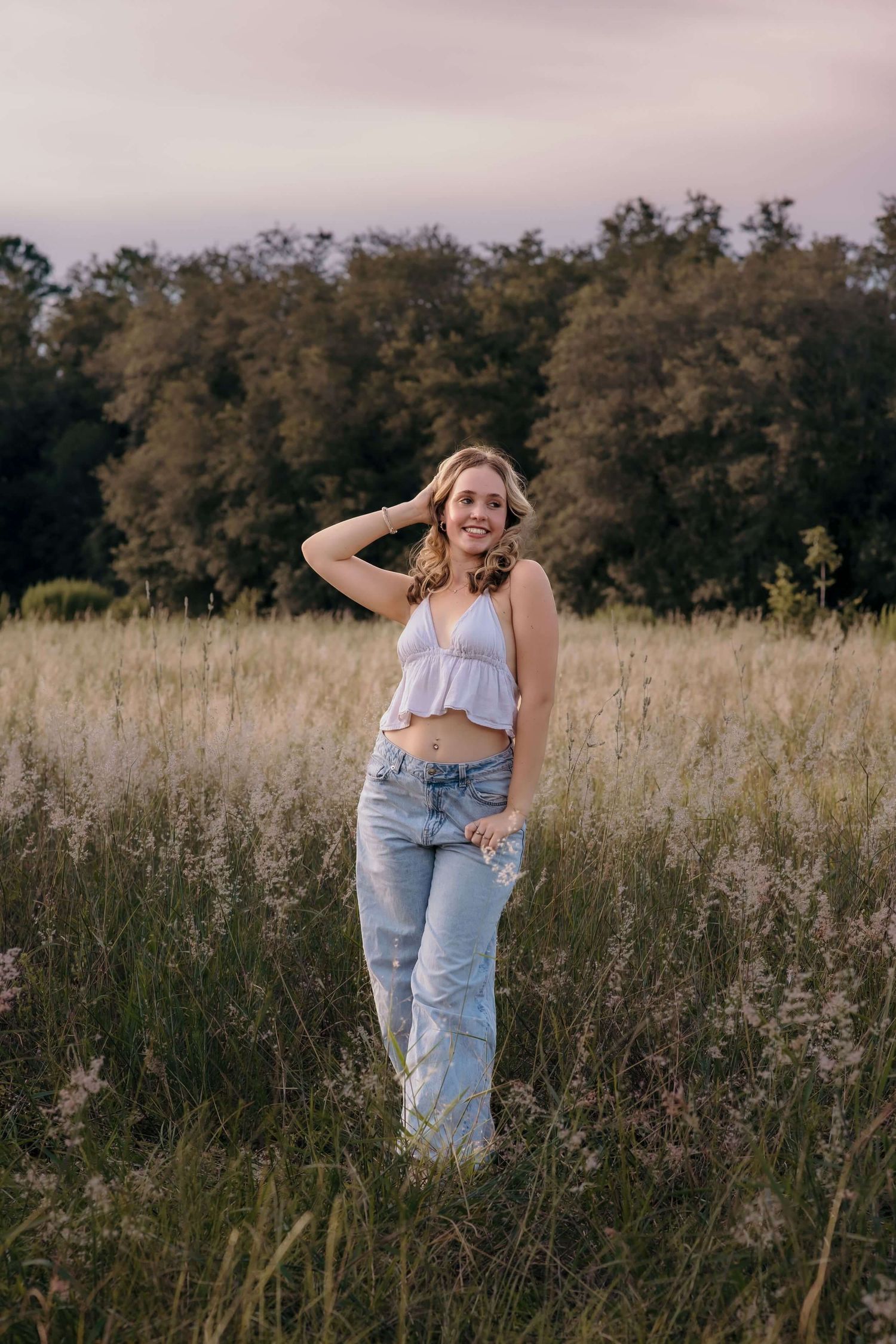 Artistic portraits in a golden field with tall grass and autumn trees in background.