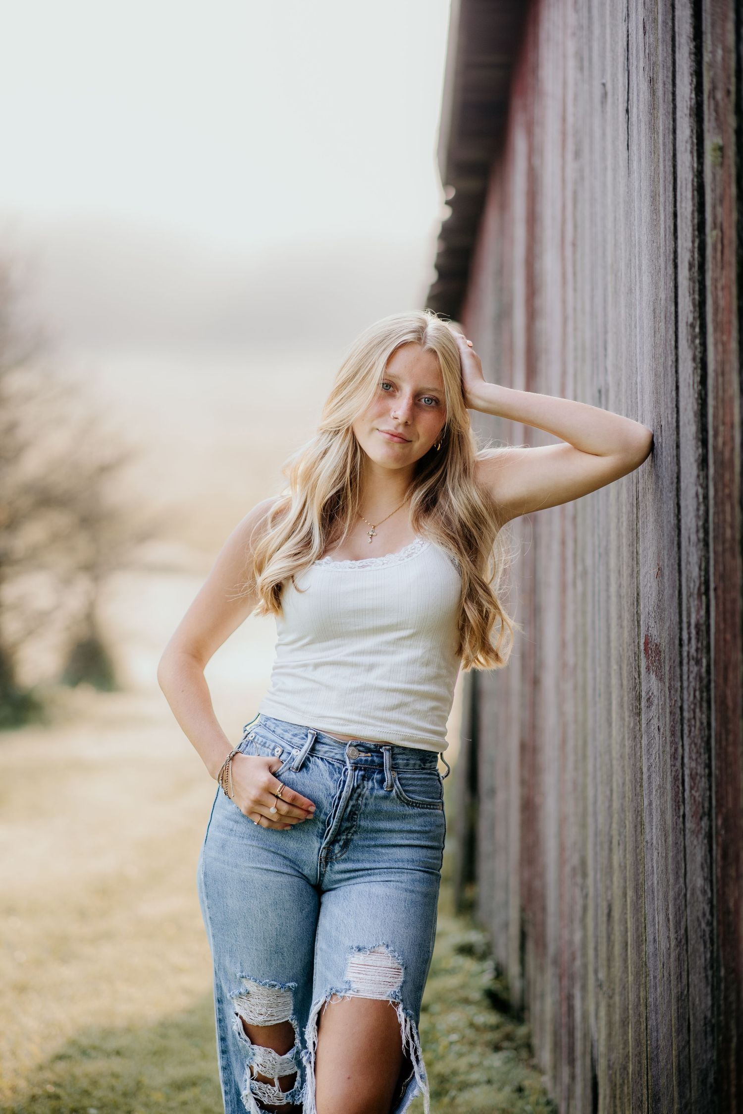 Lifestyle portrait against weathered barn wall in casual summer attire.