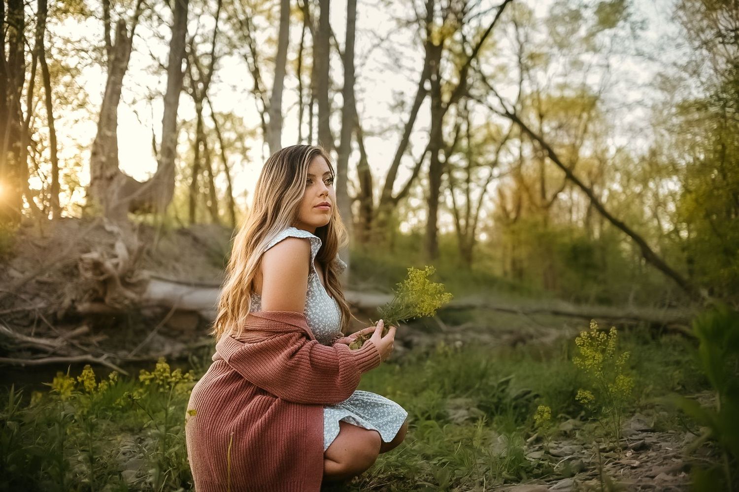 A woman in casual attire sits outdoors during golden hour.