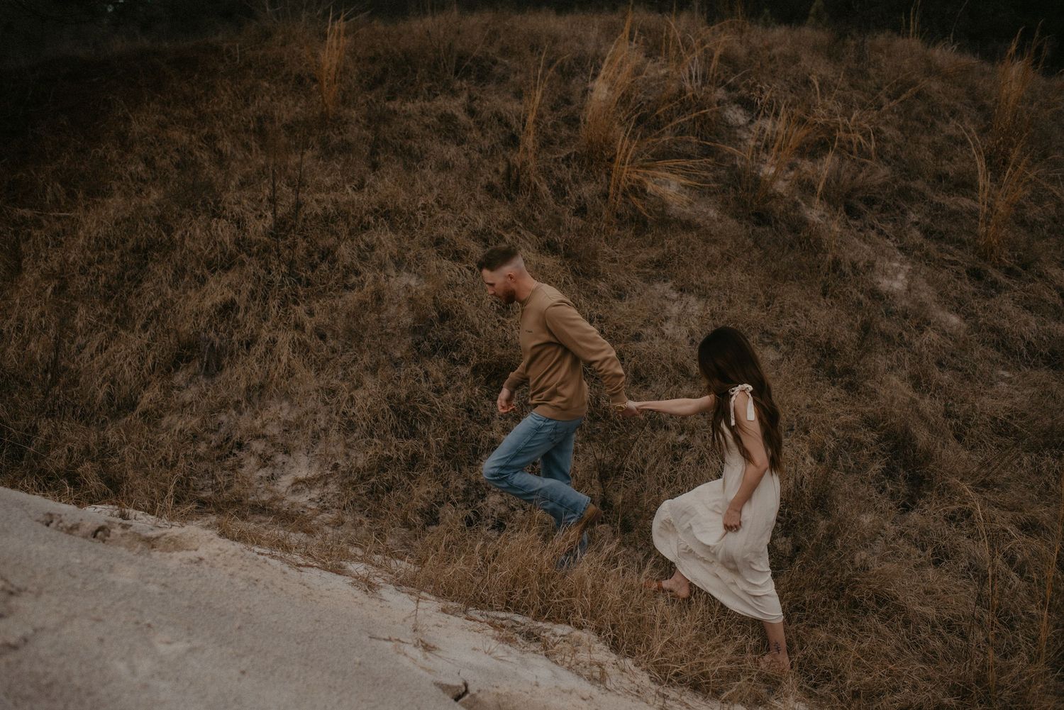 A couple embraces during a romantic sunset photoshoot on a mountainside trail.