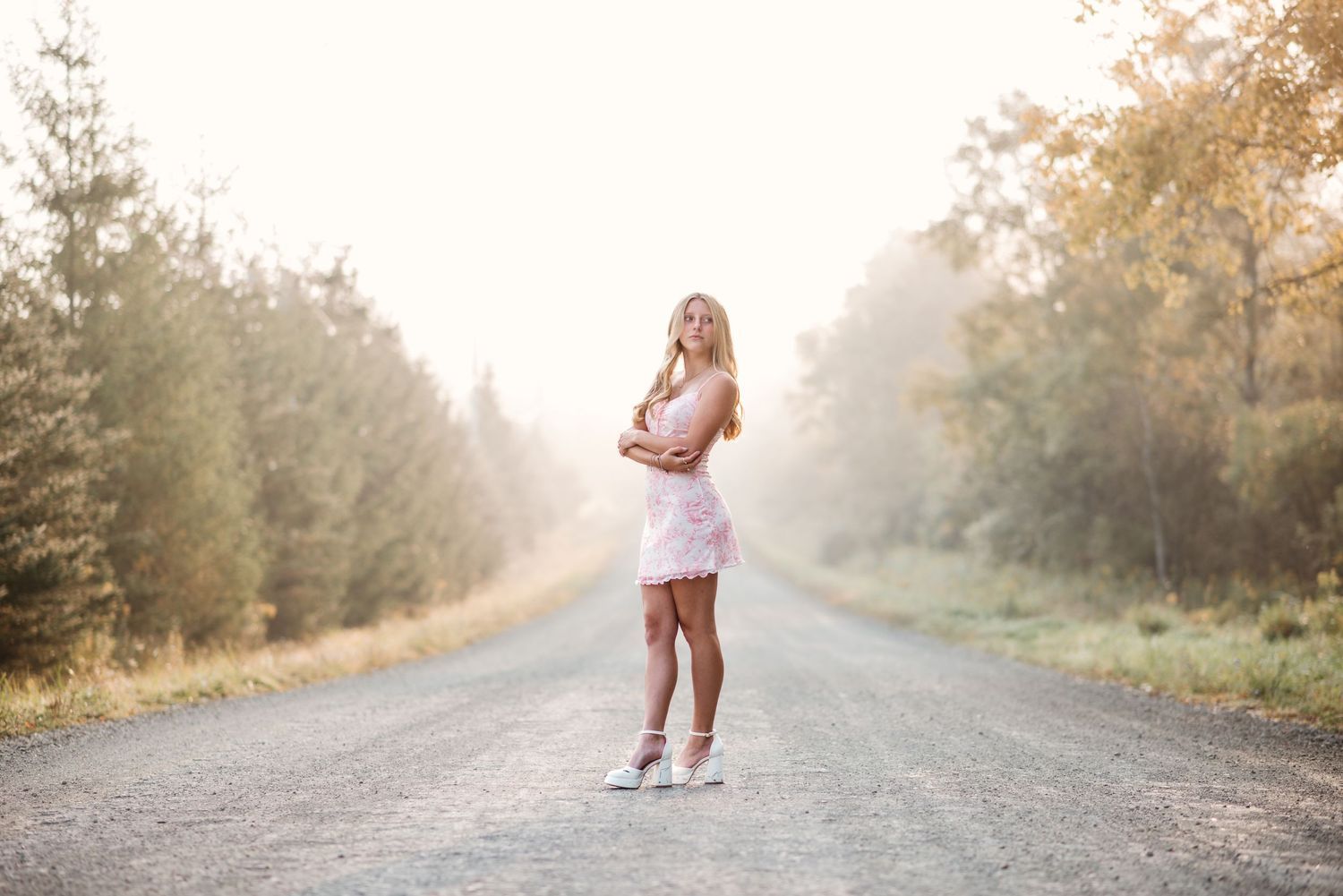 Dreamy portrait on foggy rural road in white dress.