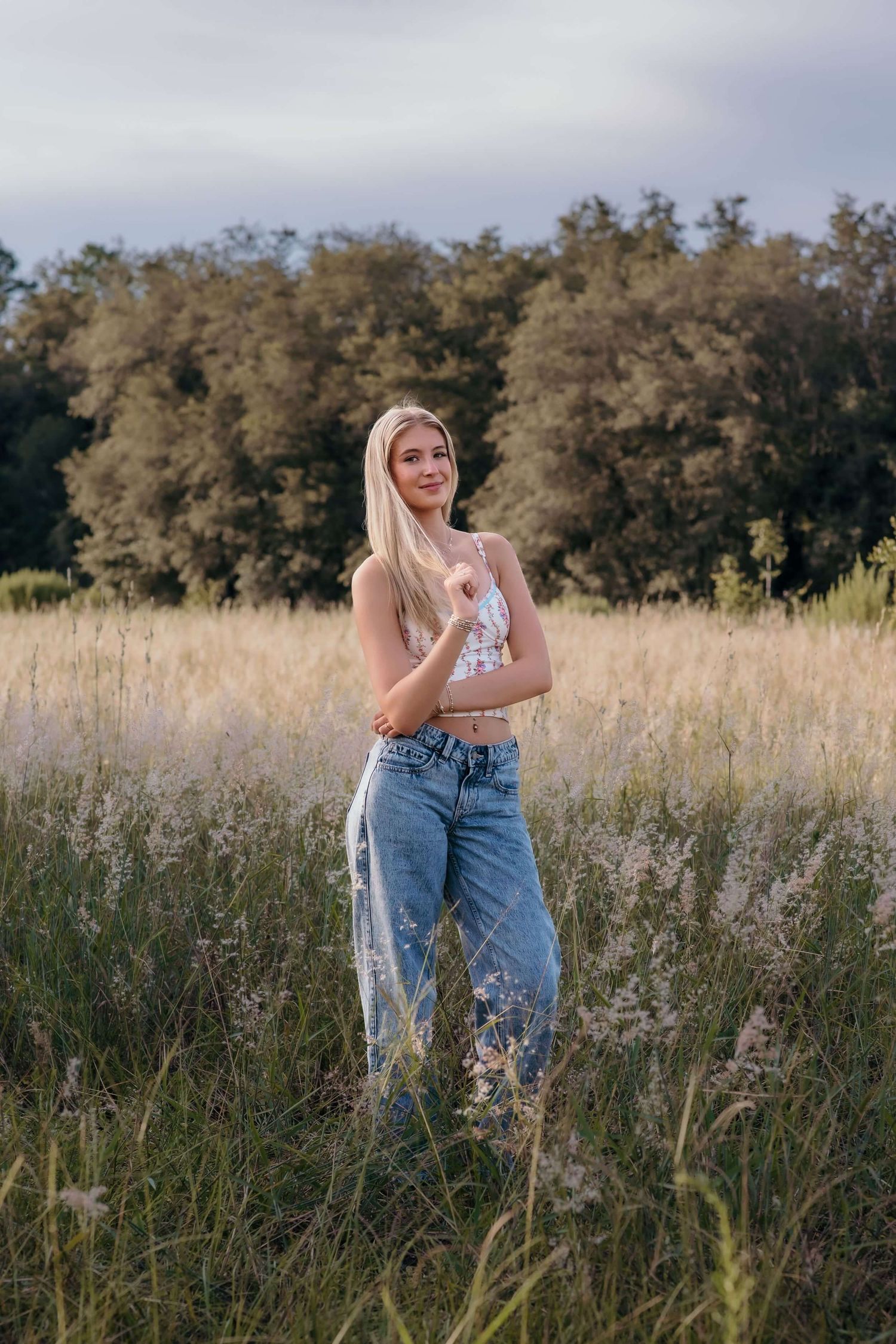 Natural outdoor photography session in a rustic field with tall grass and trees.