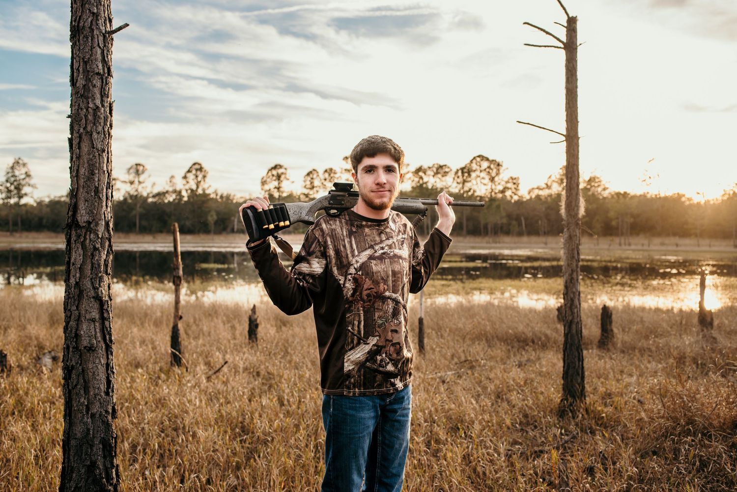 Outdoor photoshoot in natural field setting with pine trees at sunset.